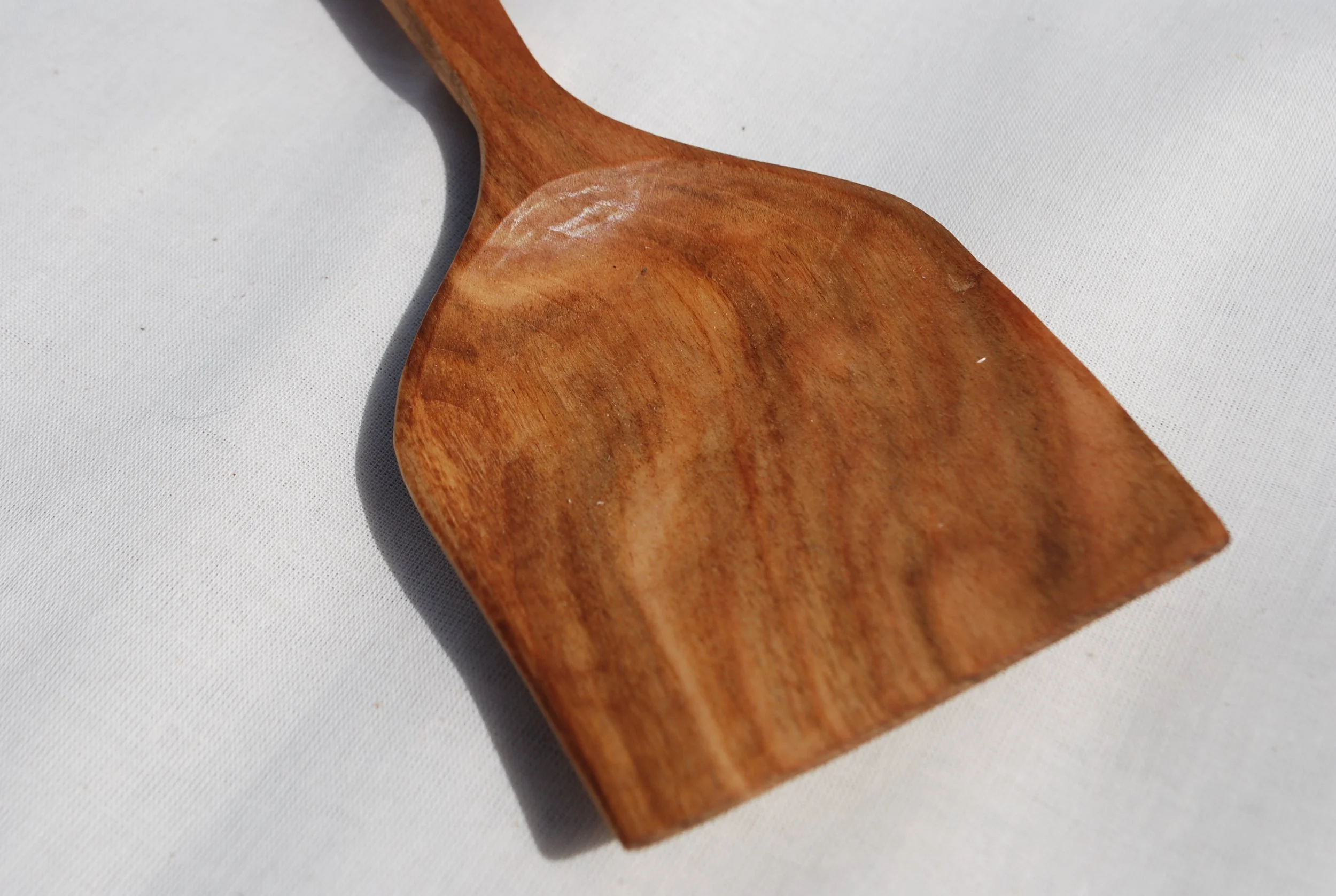 Close-up of a wooden spatula on a white surface.