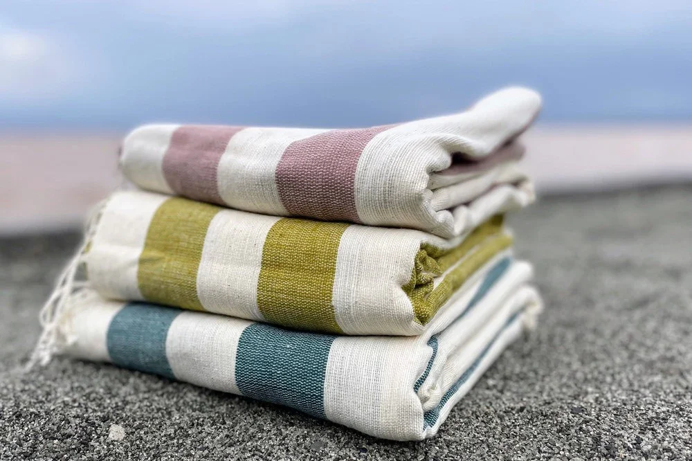 omo-towel-in-clay-moss-teal-on-sand.webp