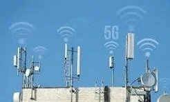 Multiple communication antennas and towers on a rooftop with 5G signal icons and Wi-Fi signals against a blue sky