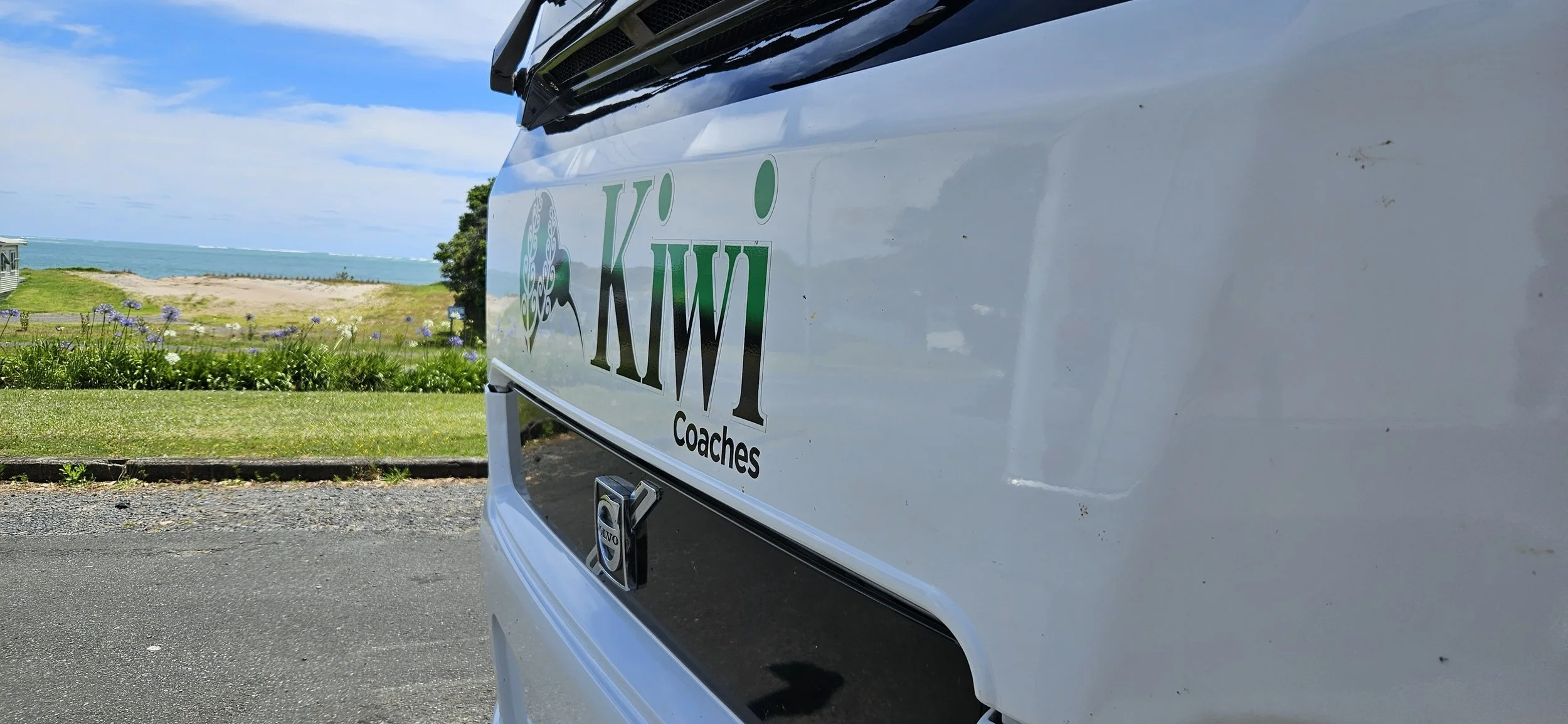 Kiwi Coaches luxury tour coach travelling through scenic New Zealand landscapes.