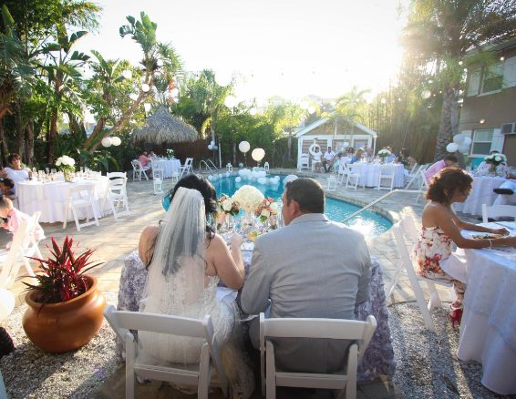 Wedding reception outdoors by a pool with guests and decorations.