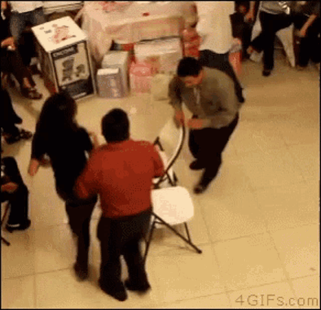 People playing musical chairs. A woman falls down.