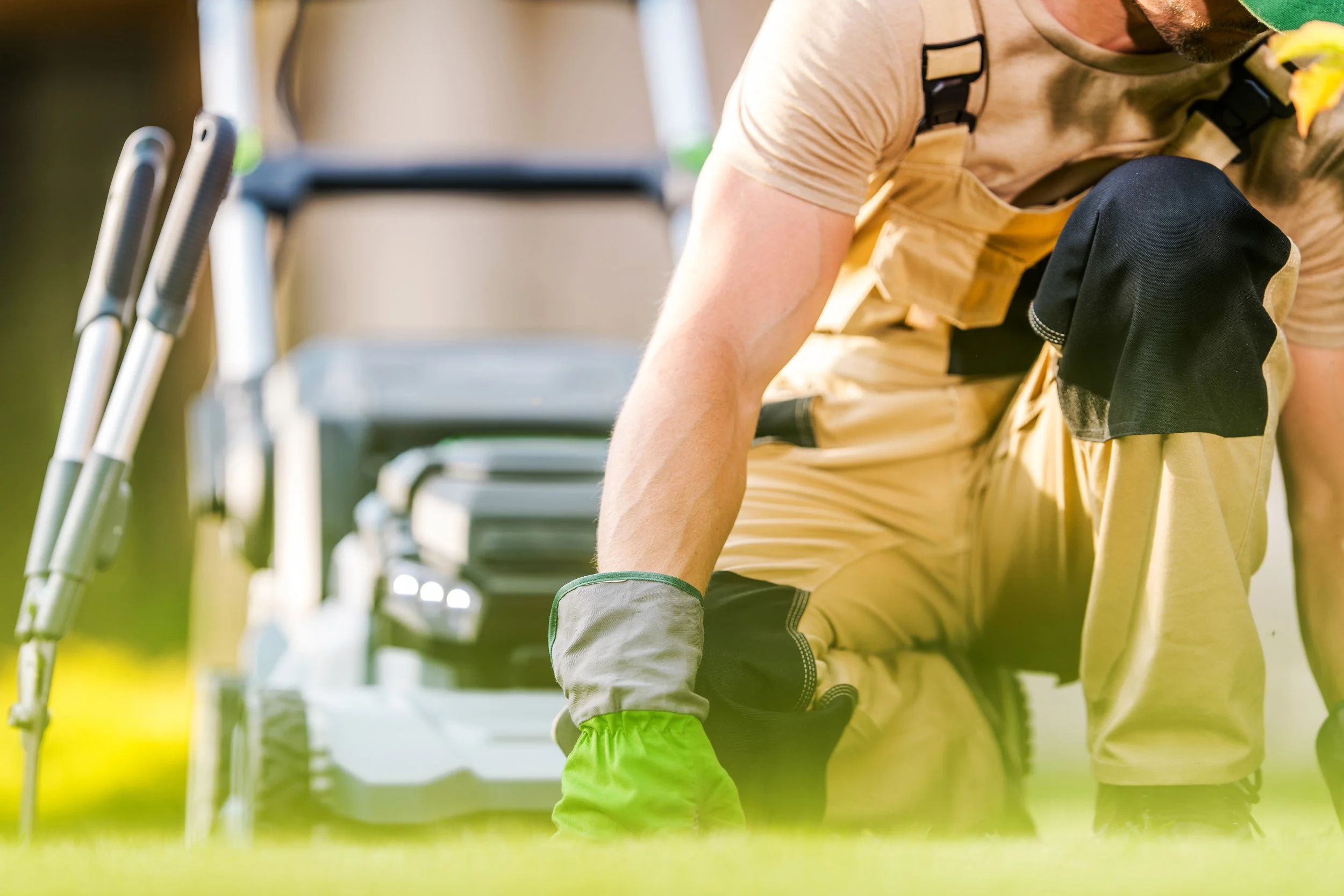 Close-up of a person in outdoor gear, reaching down with their left hand, with a row of golf carts visible in the background.