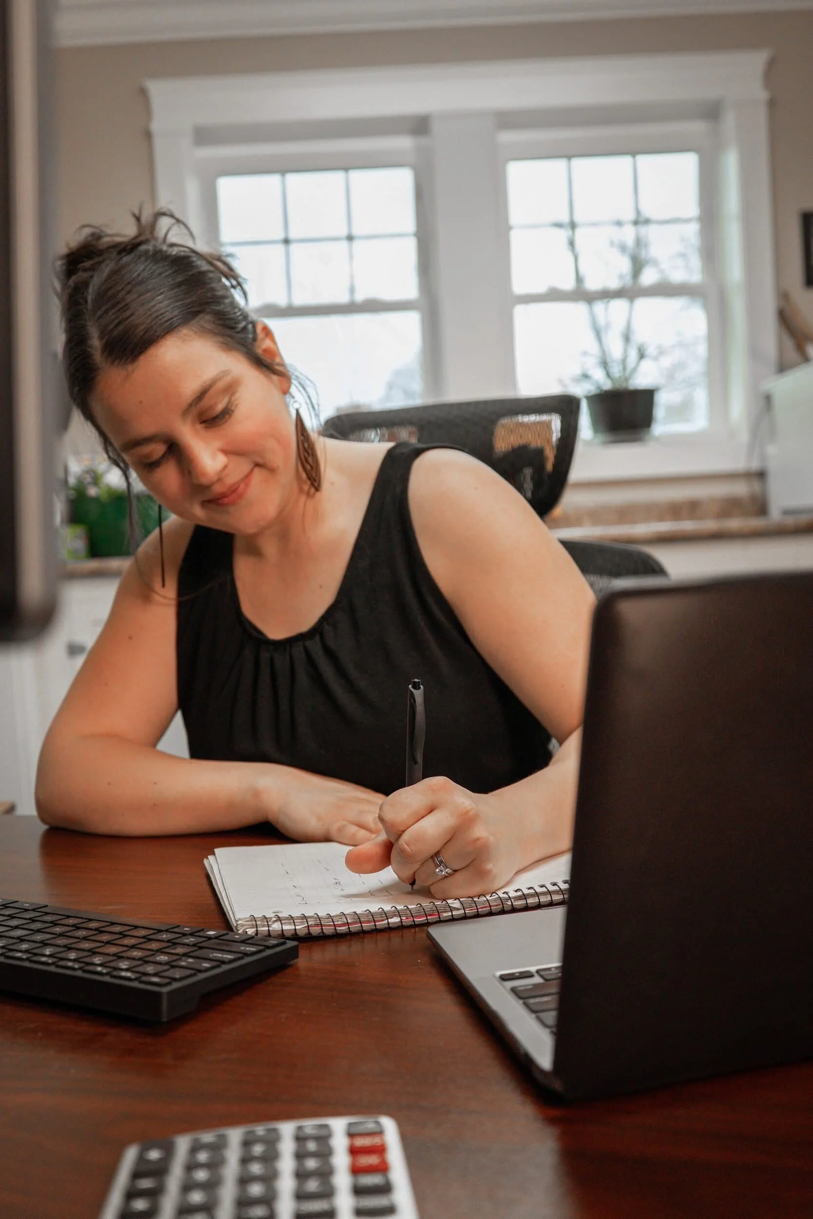 Siena Haskell writing in a notebook at her desk.