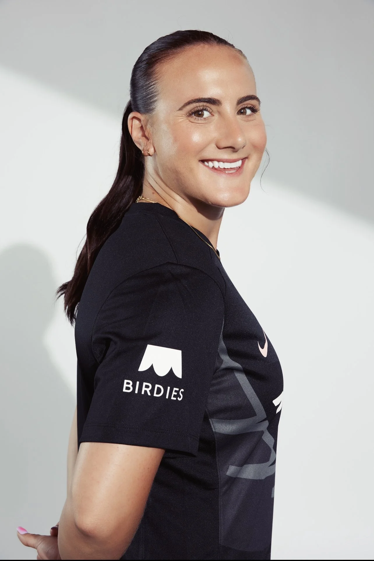 Maggie Lena professional athlete and founder of Magma Focus. Person smiling, wearing a black shirt with 'BIRDIES' logo on the sleeve.