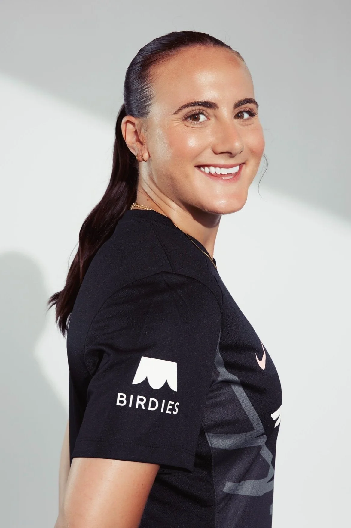 Smiling person wearing a black t-shirt with "Birdies" logo on the sleeve.