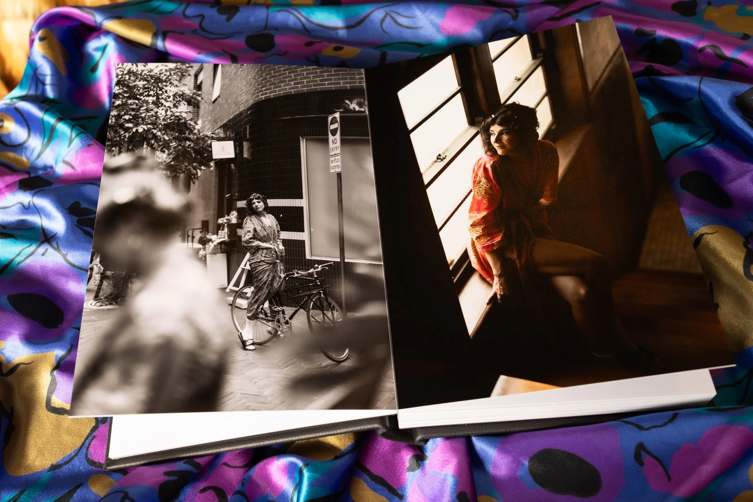 Photographs of a woman with curly hair, one outdoor black-and-white photo showing her standing with a bicycle in an urban environment, and a colorful indoor photo showing her sitting near a window with light shining on her face, wearing a patterned shirt.