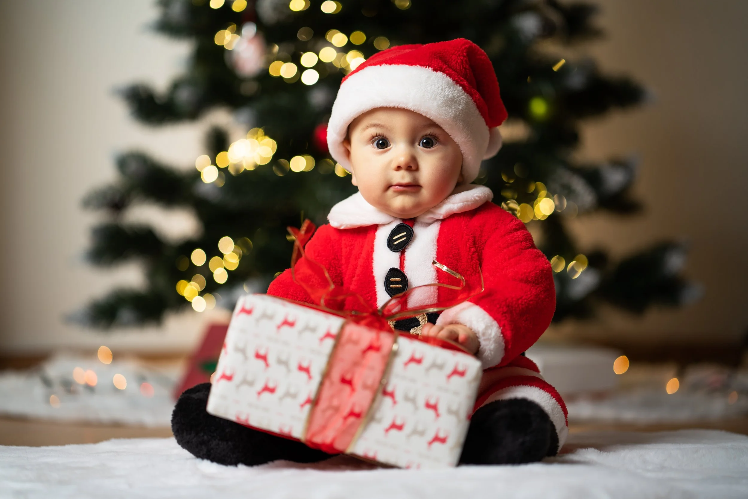 Boy Christmas in Santa outfit with a present