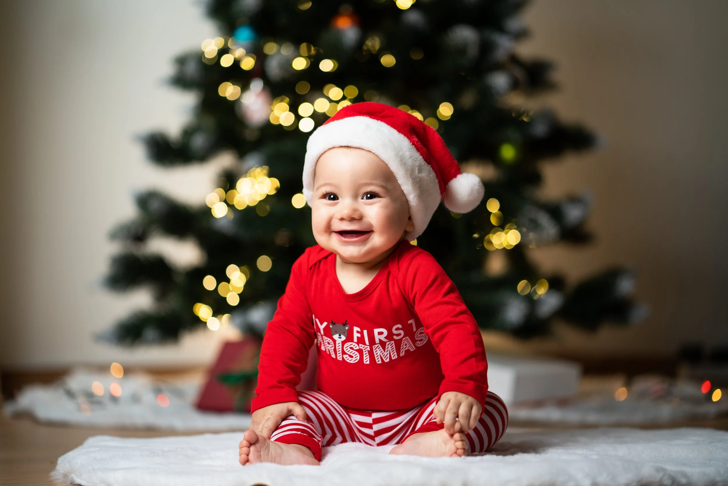 Boy Christmas Smiling sitting in front of Christmas Tree