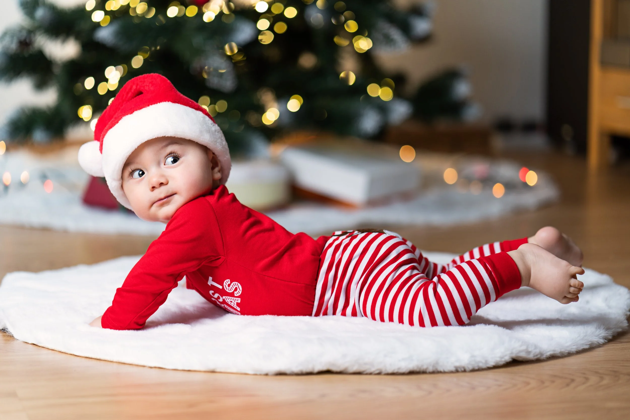 Boy Christmas Lying sideways in front of Christmas Tree