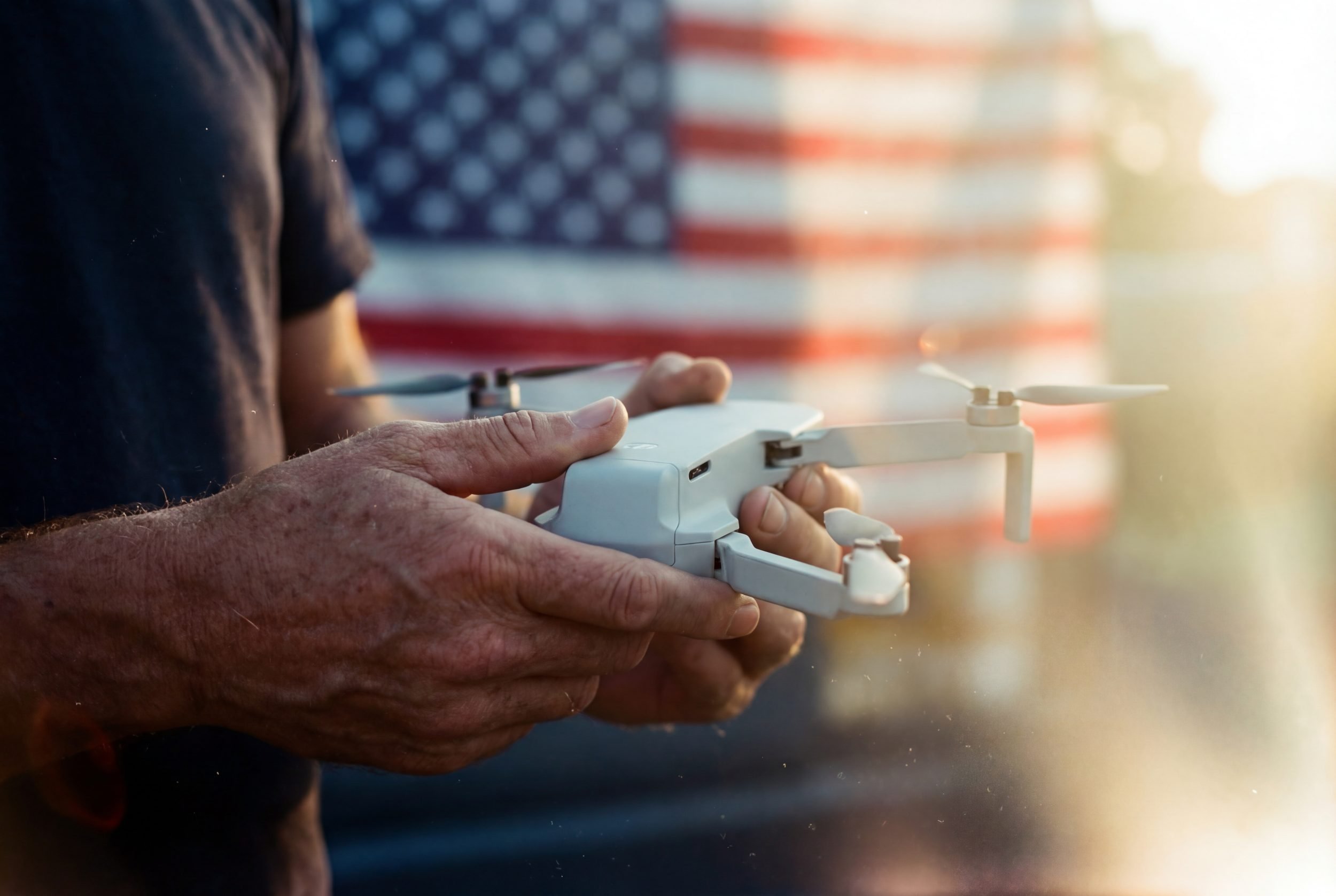 Drone pilot preparing an unbranded drone with an American flag in the background, representing questions around U.S. drone market replacements.