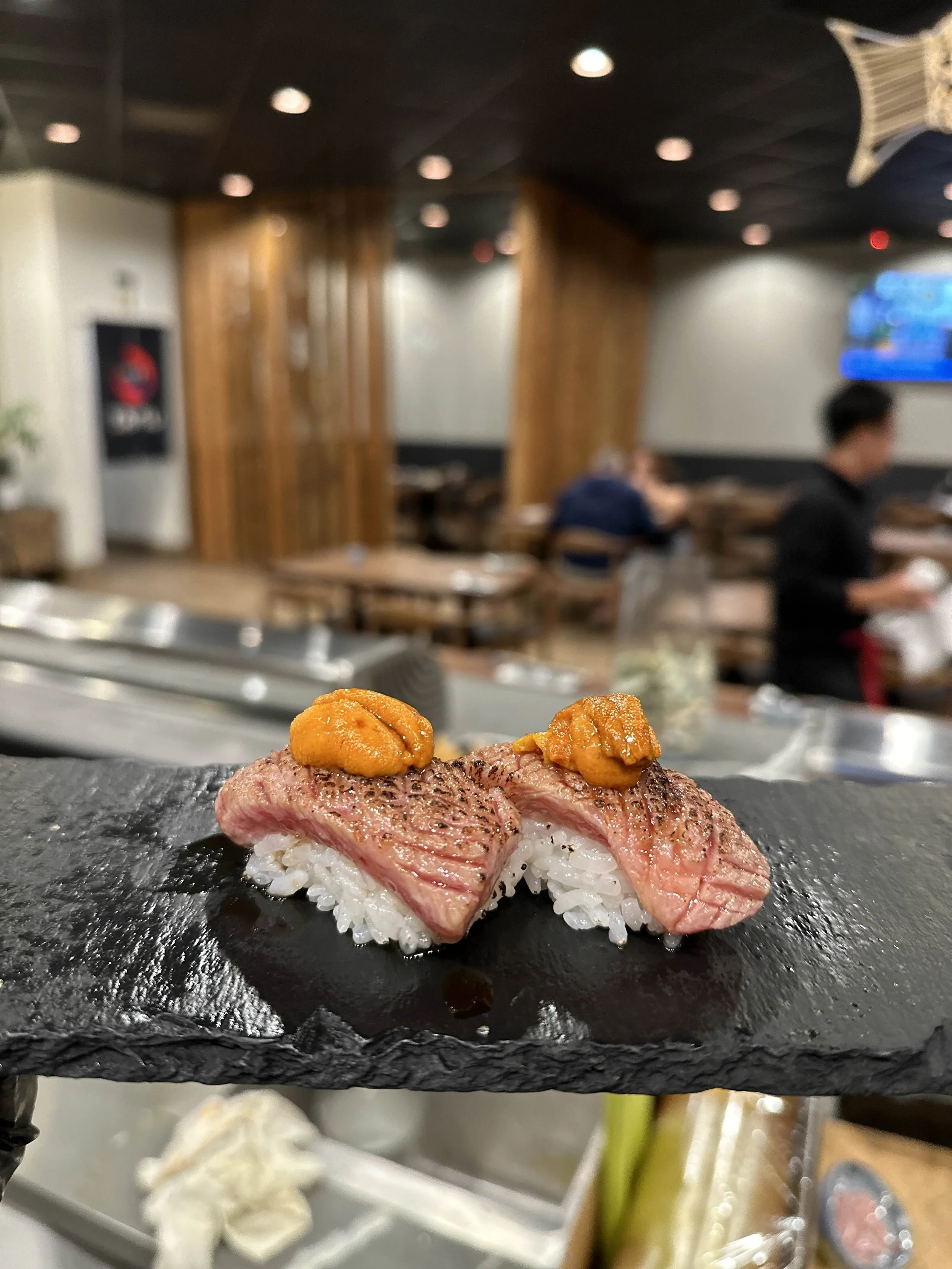 Plate of sushi topped with sea urchin on a restaurant counter.