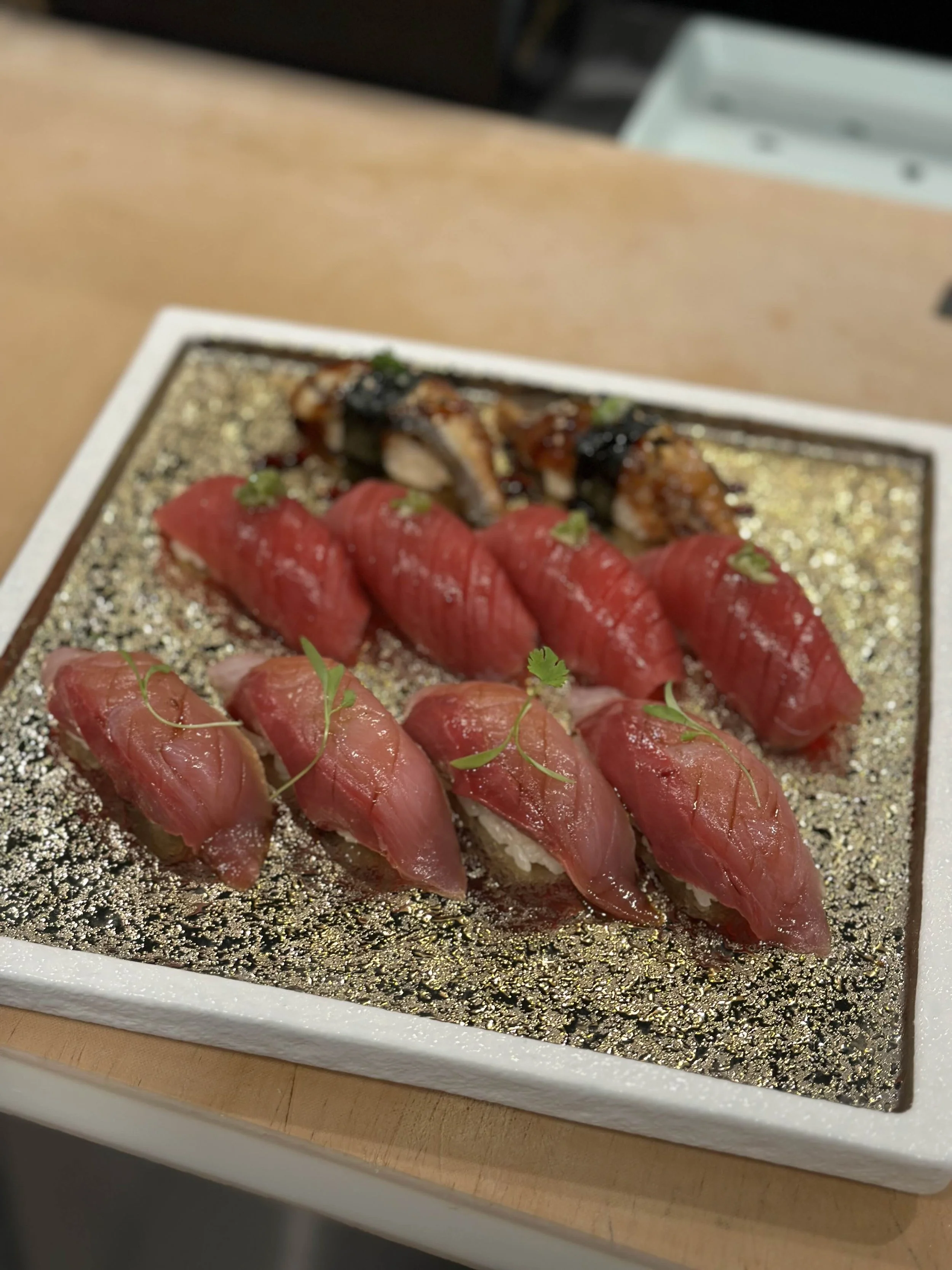 Plate of assorted sushi including nigiri with fish topping and garnishes, on a decorative platter.