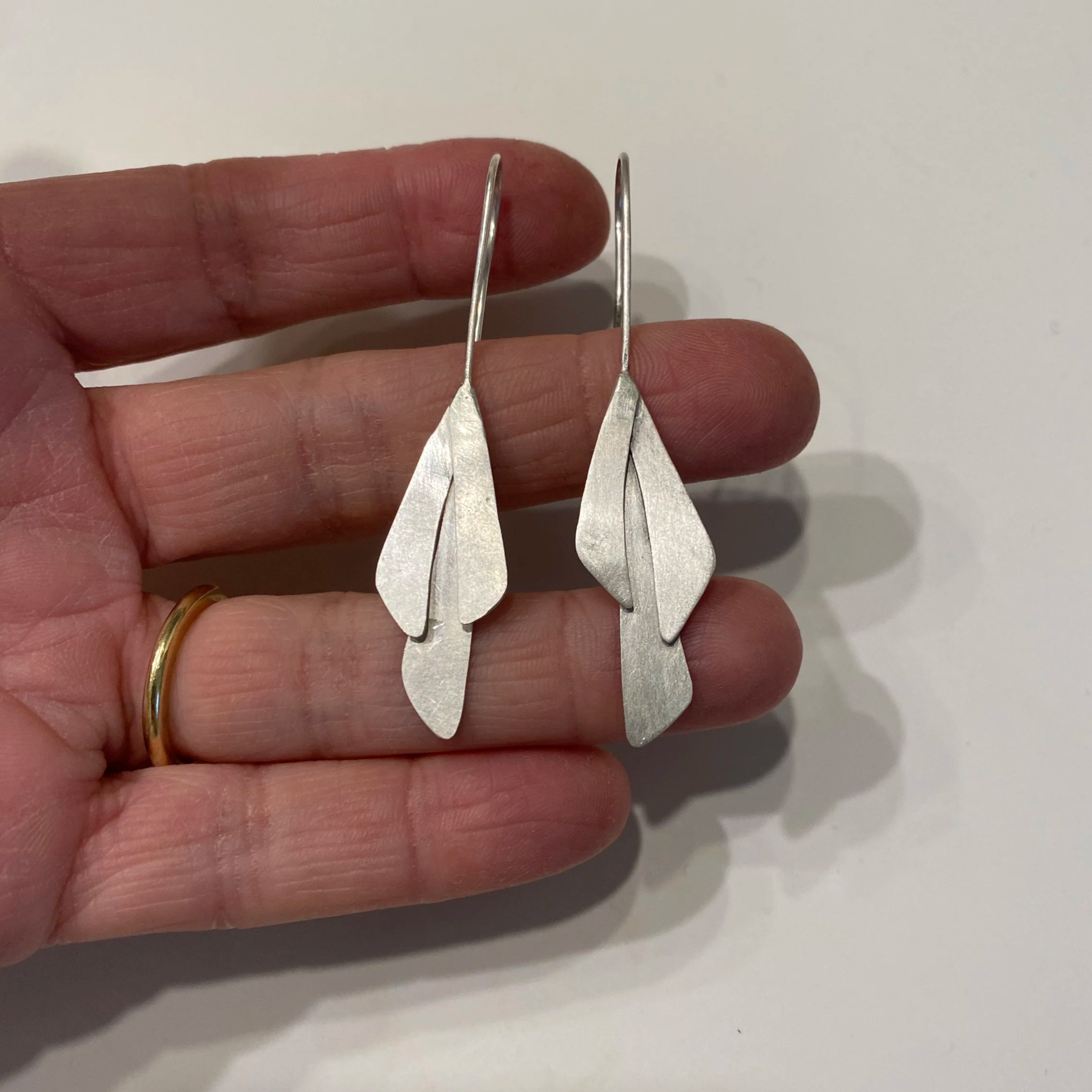 Long Leaves – Earrings in silver: Long silver leaf earrings handmade in Switzerland, contemporary jewelry with matte and polished textures catching light