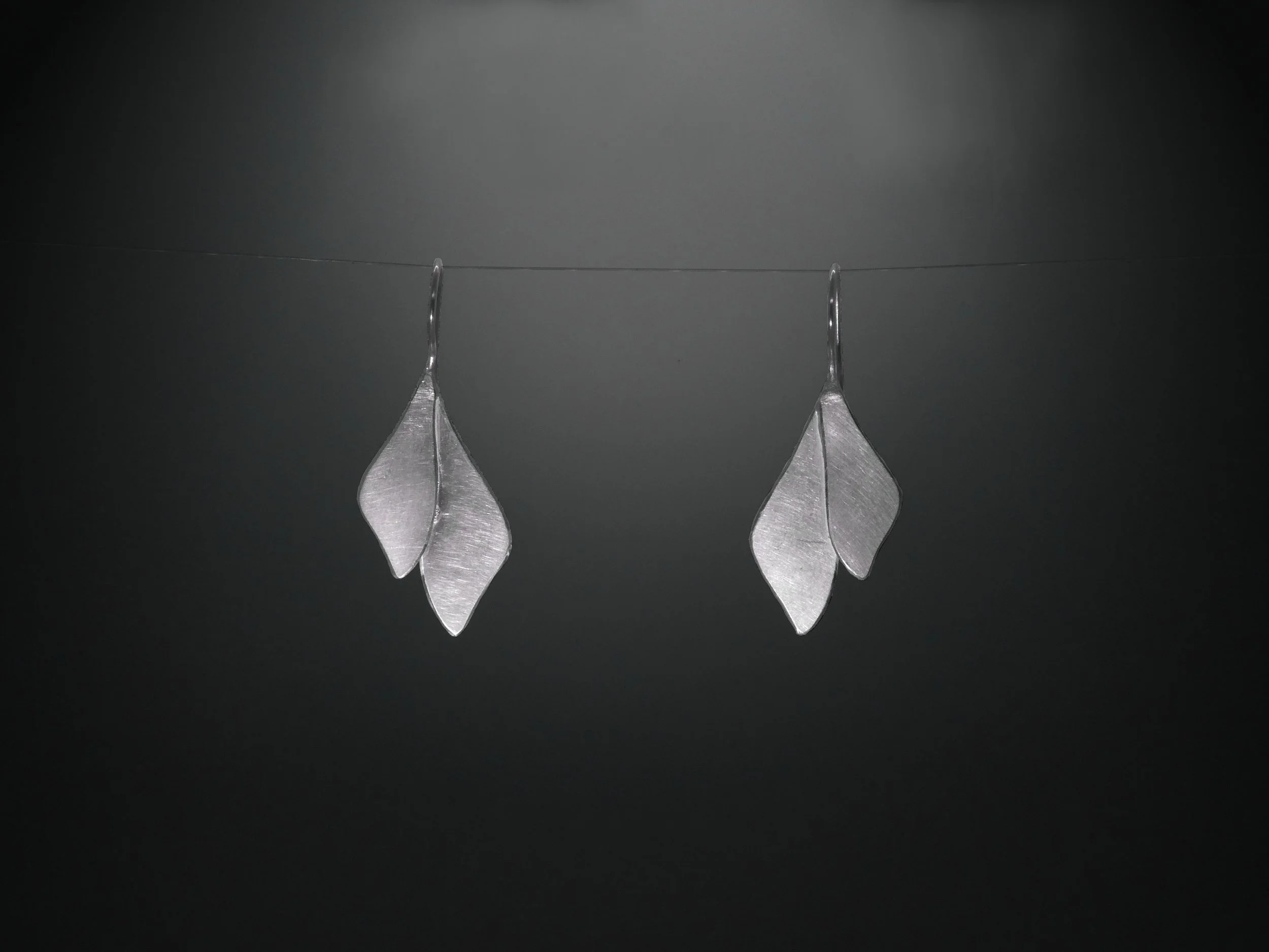 Silver leaf earrings handmade in Switzerland by Julie Usel, contemporary jewelry with matte and polished textures reflecting light