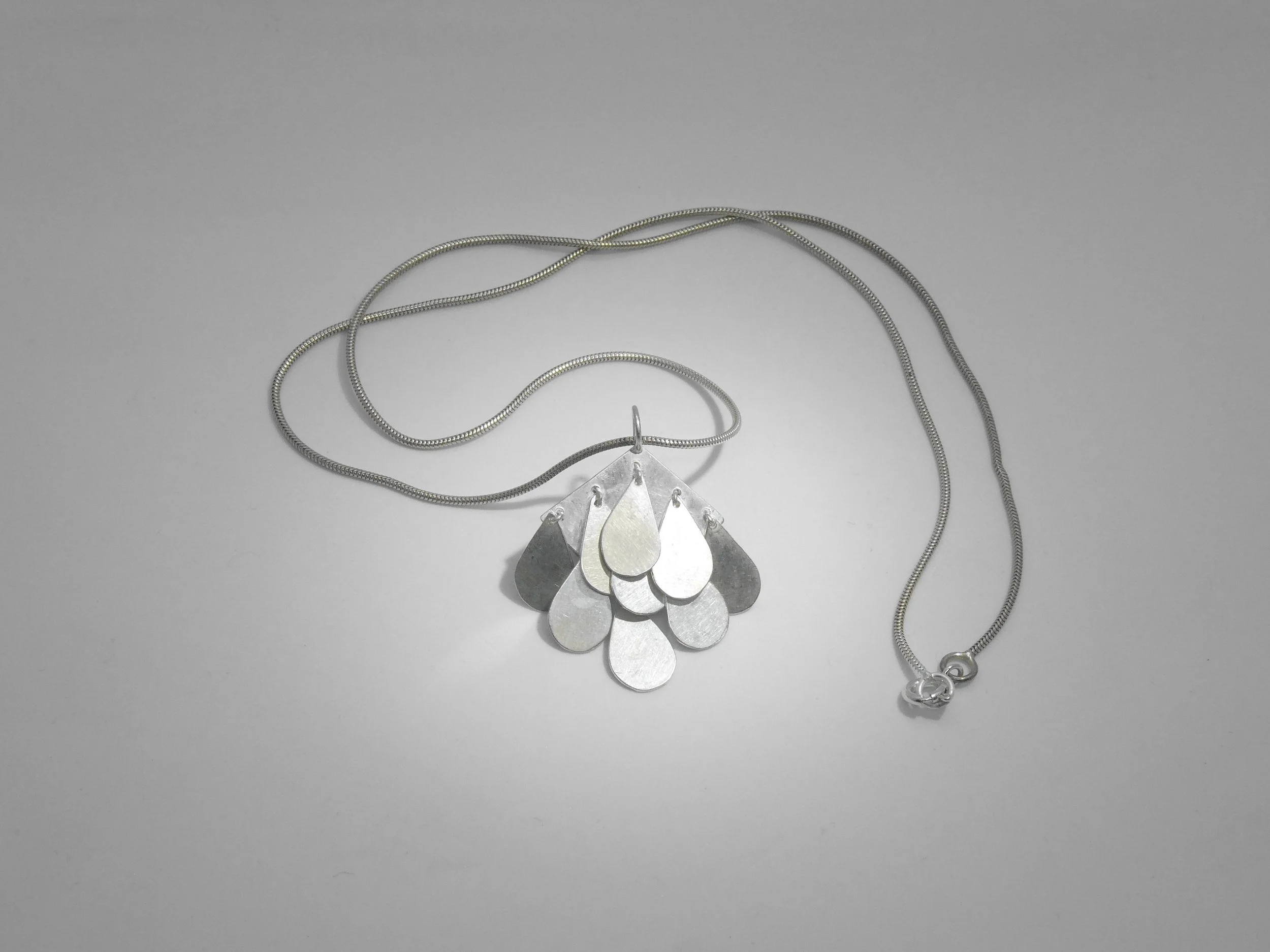 Contemporary silver pendant with moving drops, handmade jewelry Switzerland reflecting light and motion