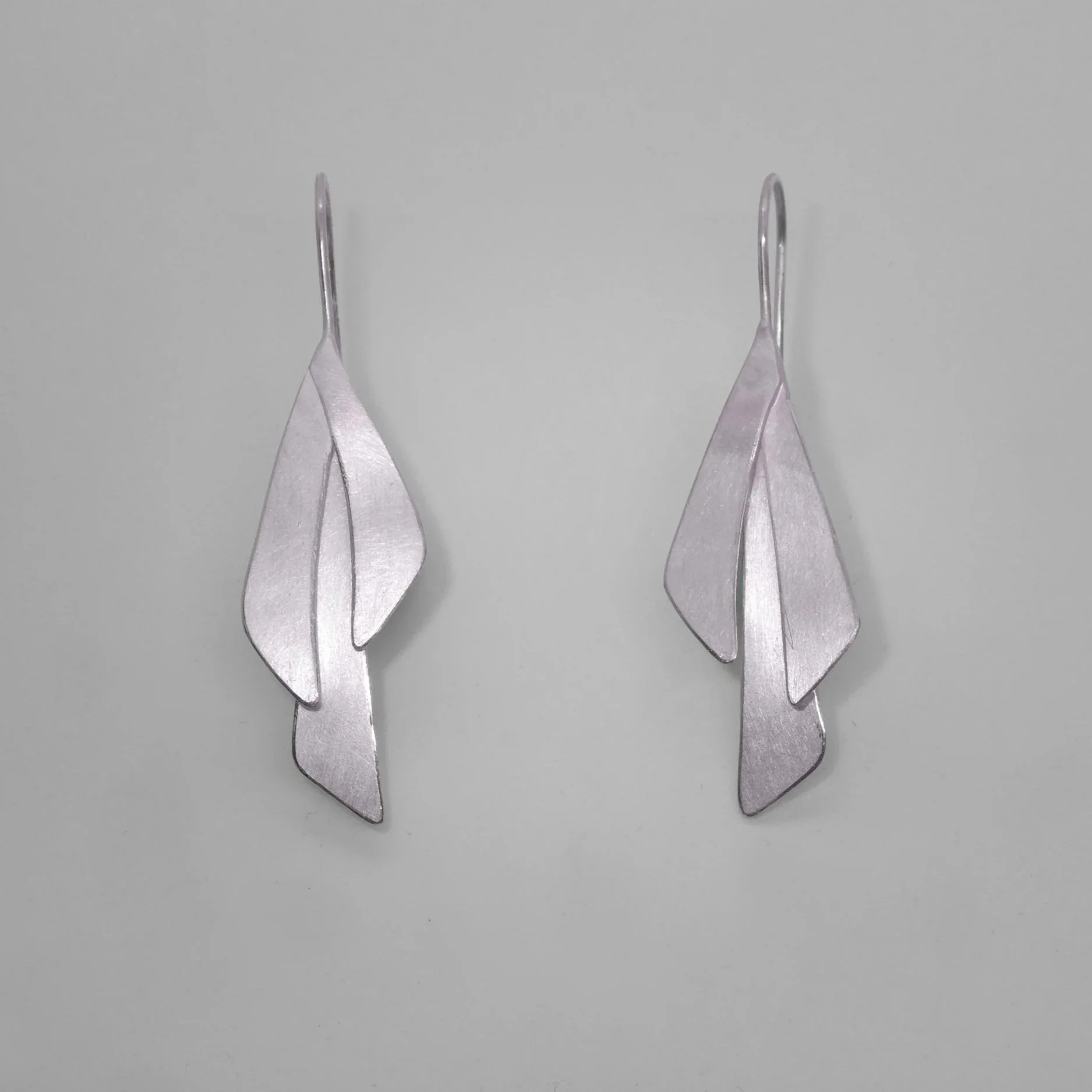 Long Leaves – Earrings in silver: Long silver leaf earrings handmade in Switzerland, contemporary jewelry with matte and polished textures catching light