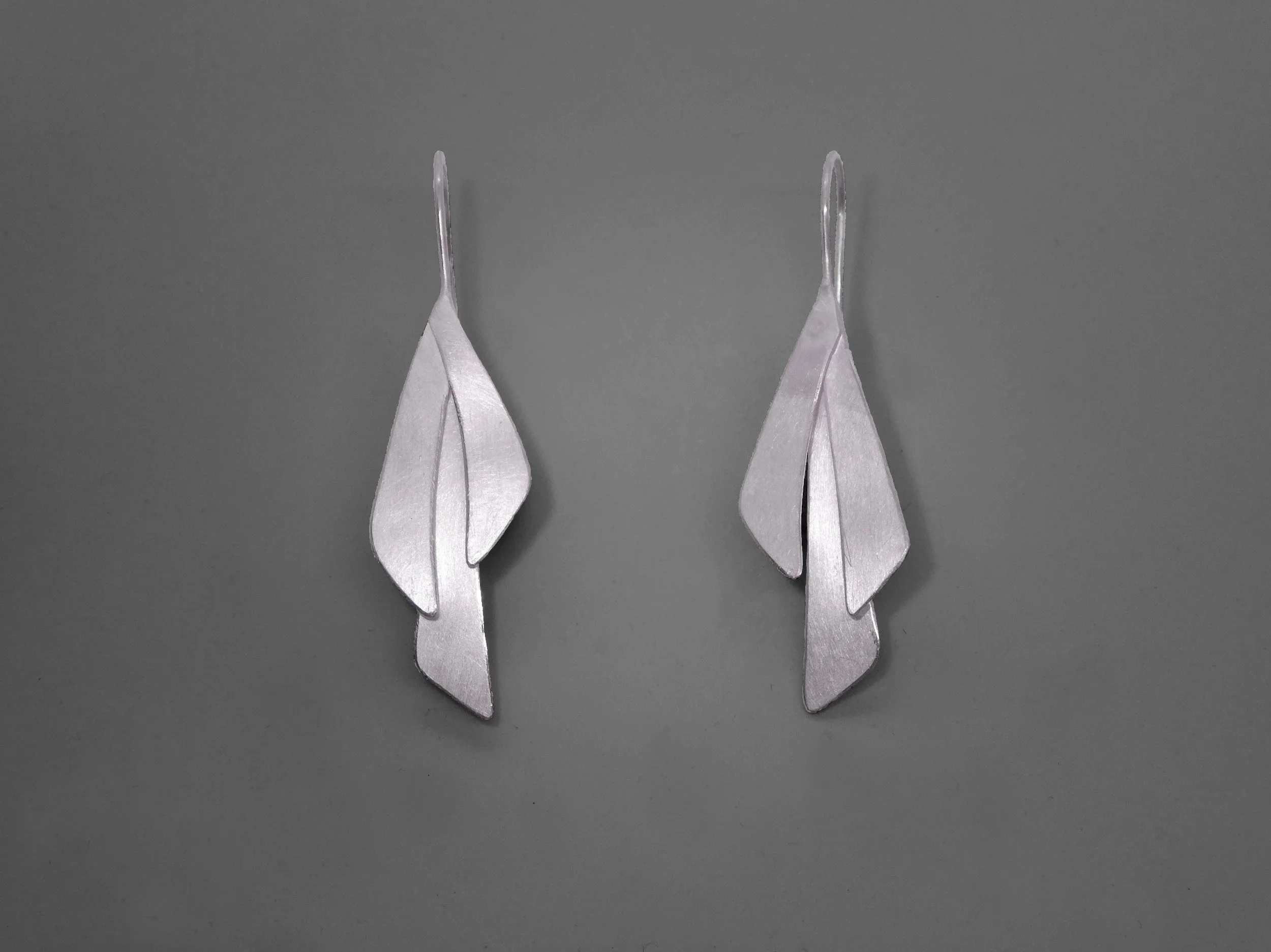 Long Leaves – Earrings in silver: Long silver leaf earrings handmade in Switzerland, contemporary jewelry with matte and polished textures catching light