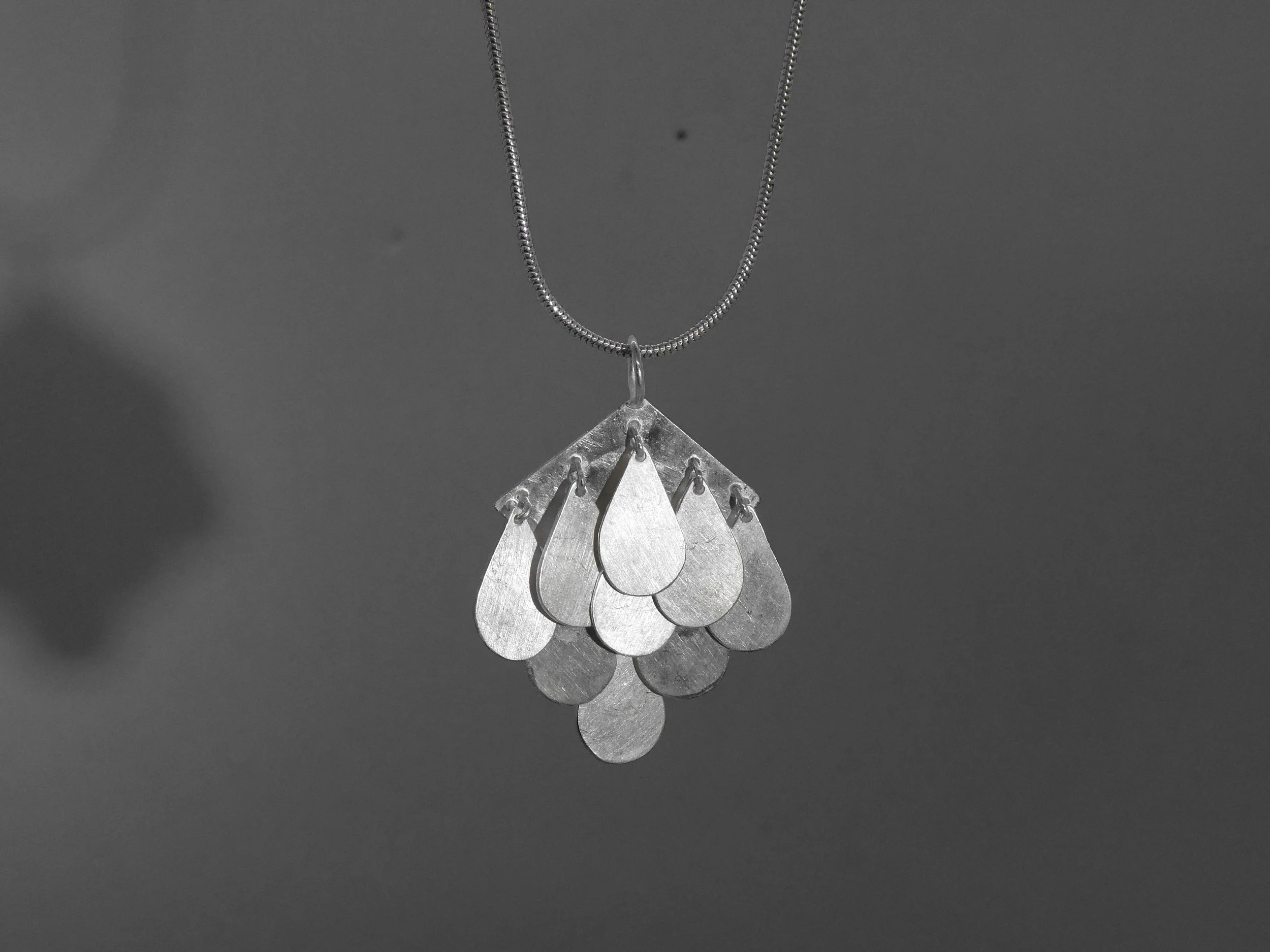 Contemporary silver pendant with moving drops, handmade jewelry Switzerland reflecting light and motion