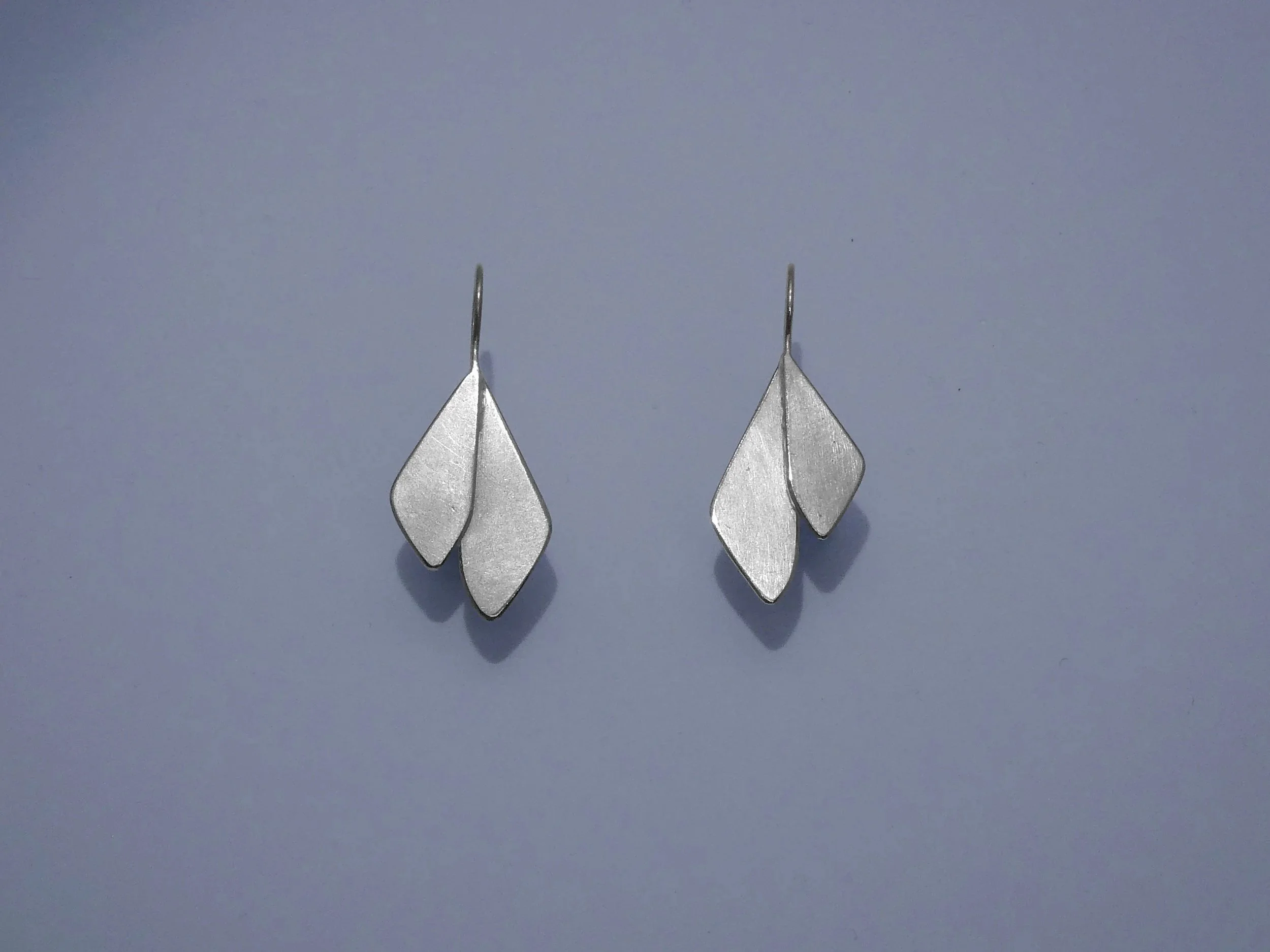 Silver leaf earrings handmade in Switzerland by Julie Usel, contemporary jewelry with matte and polished textures reflecting light