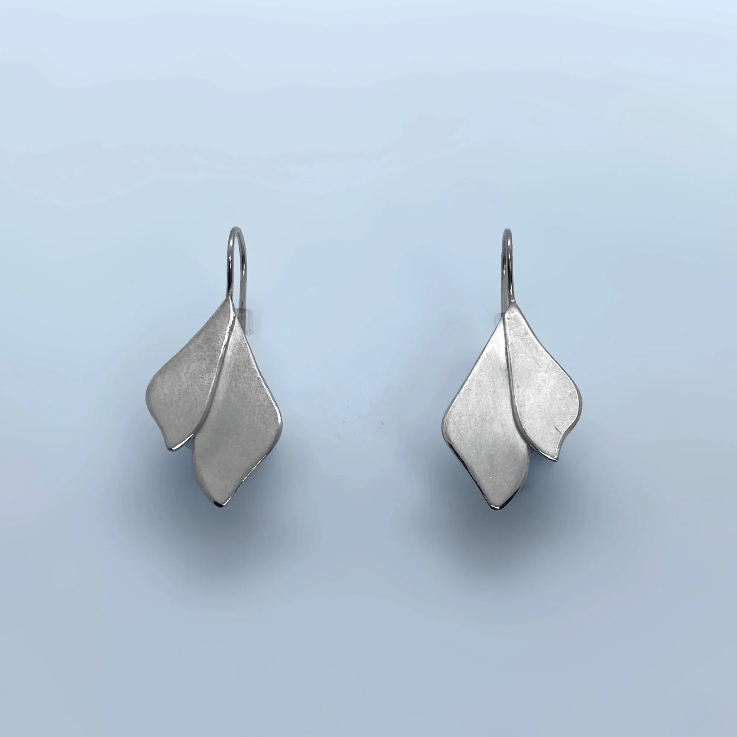 Silver leaf earrings handmade in Switzerland by Julie Usel, contemporary jewelry with matte and polished textures reflecting light