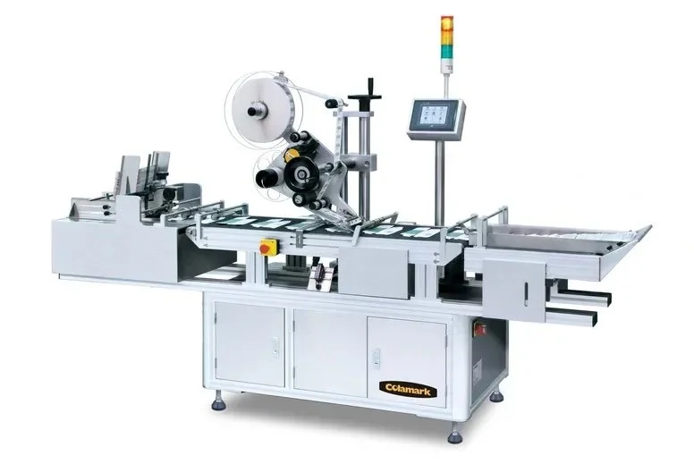 Industrial packaging or labeling machine with conveyor, control panel, and safety light tower.