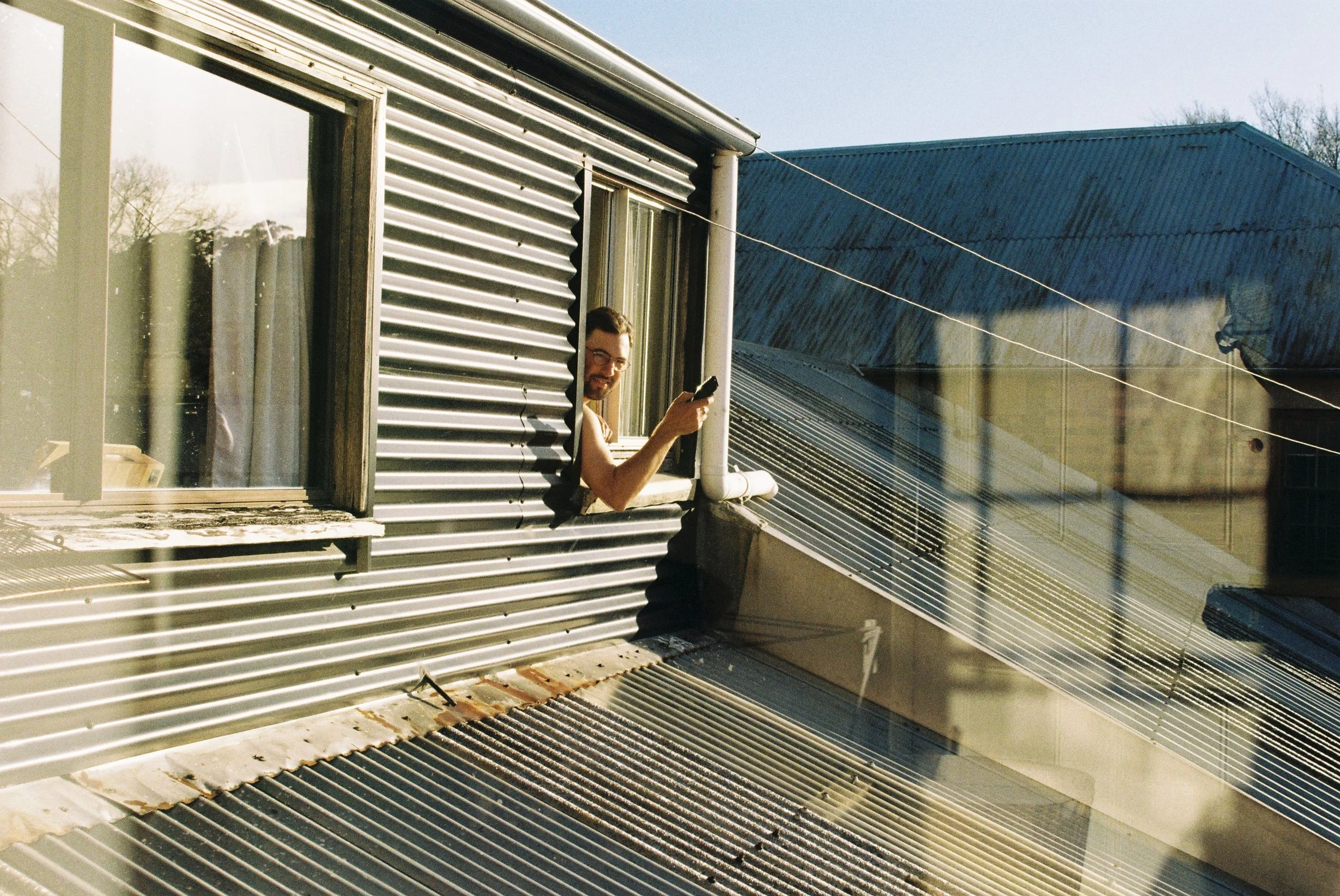Man holding electric razor while shaving out the window