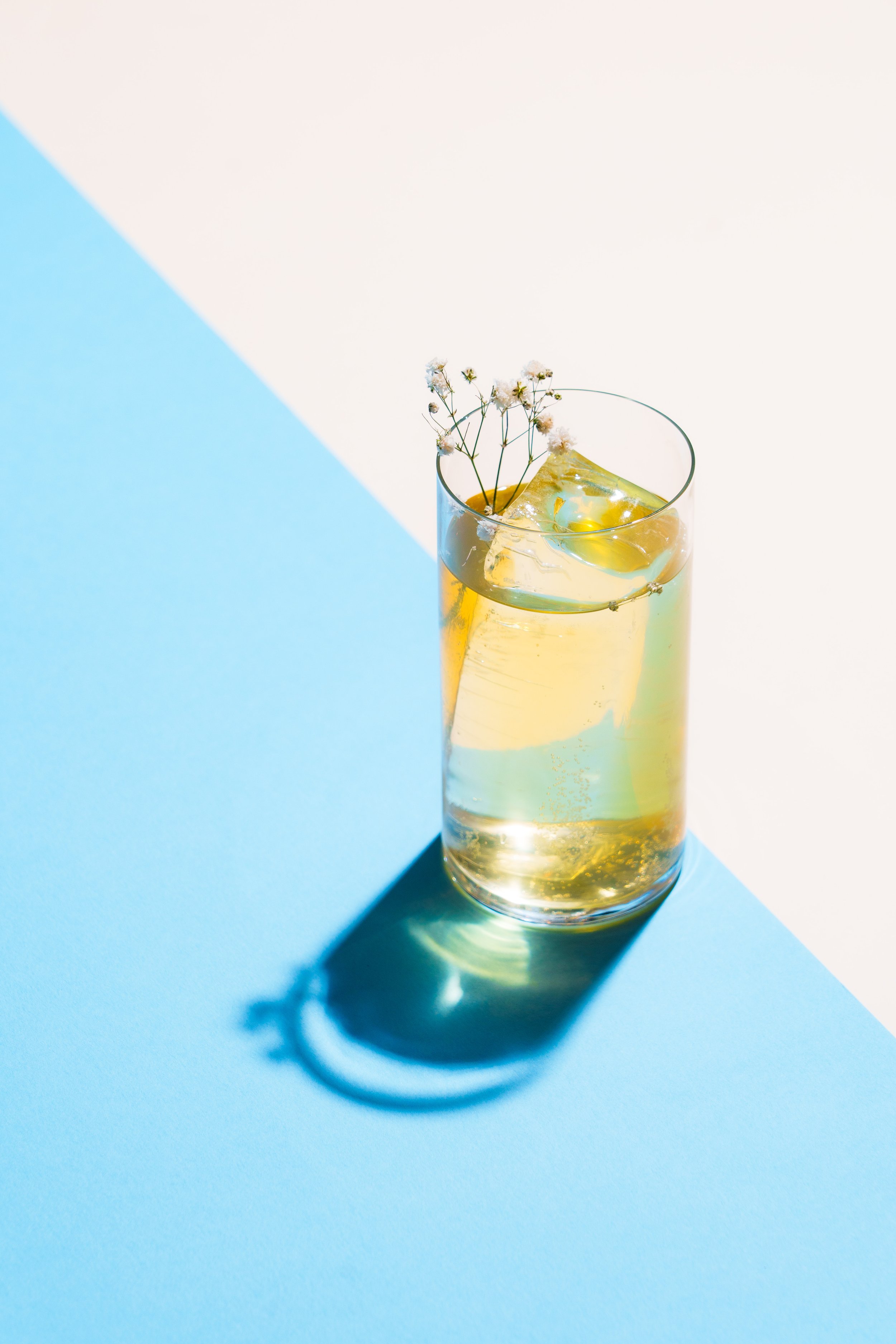 A bright cocktail on a blue background representing Mothership’s distinctive drink style