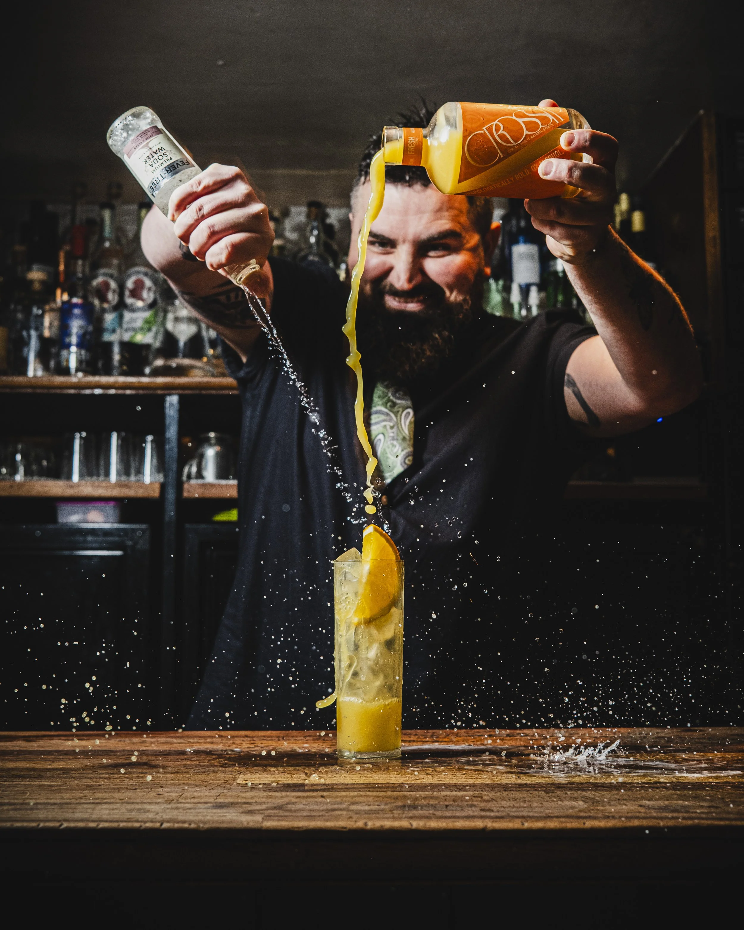 A bartender energetically pouring cocktails behind the bar, representing Mothership’s creativity and energy.