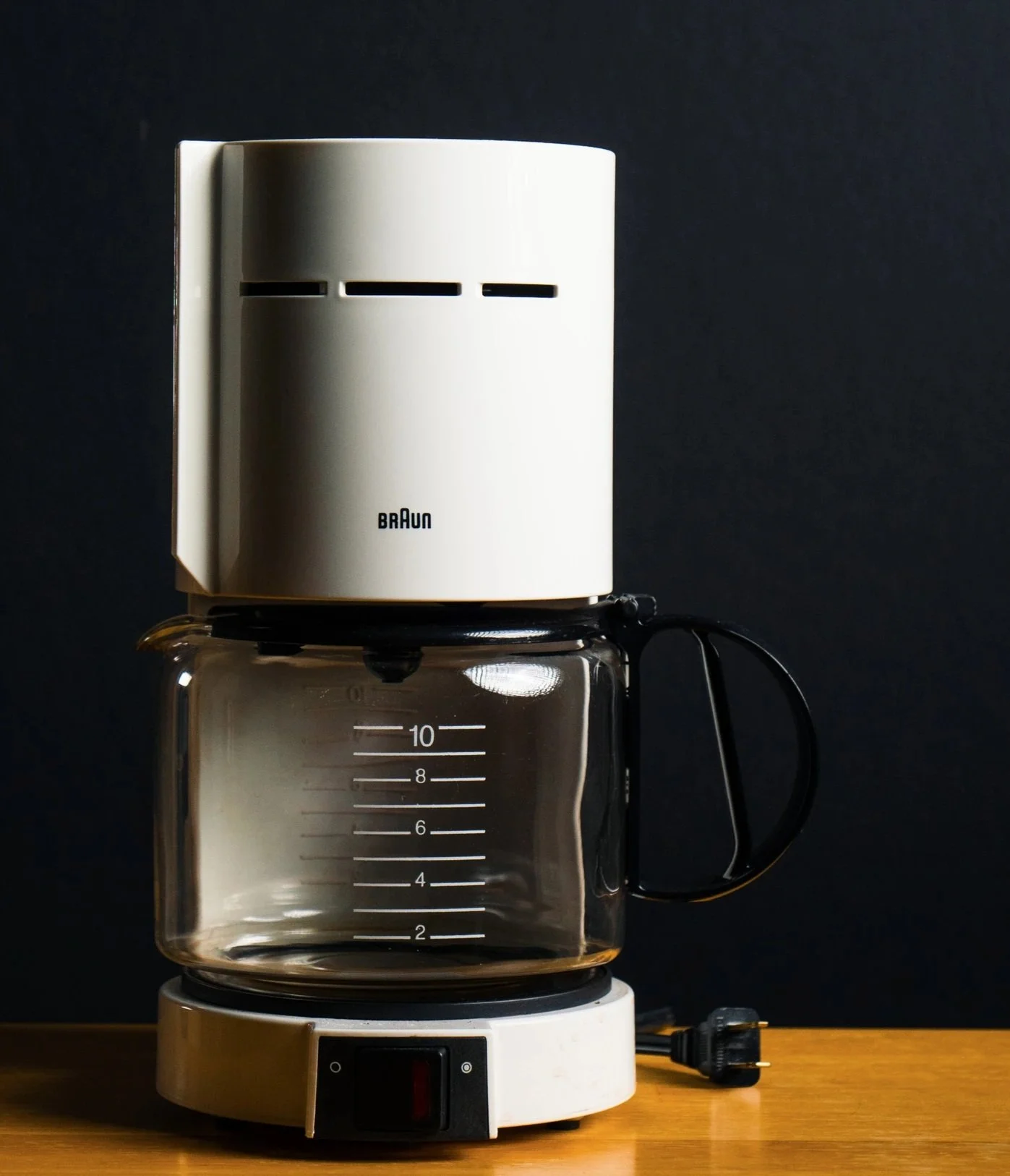 Coffee maker on a kitchen counter with a glass pot and dark background.