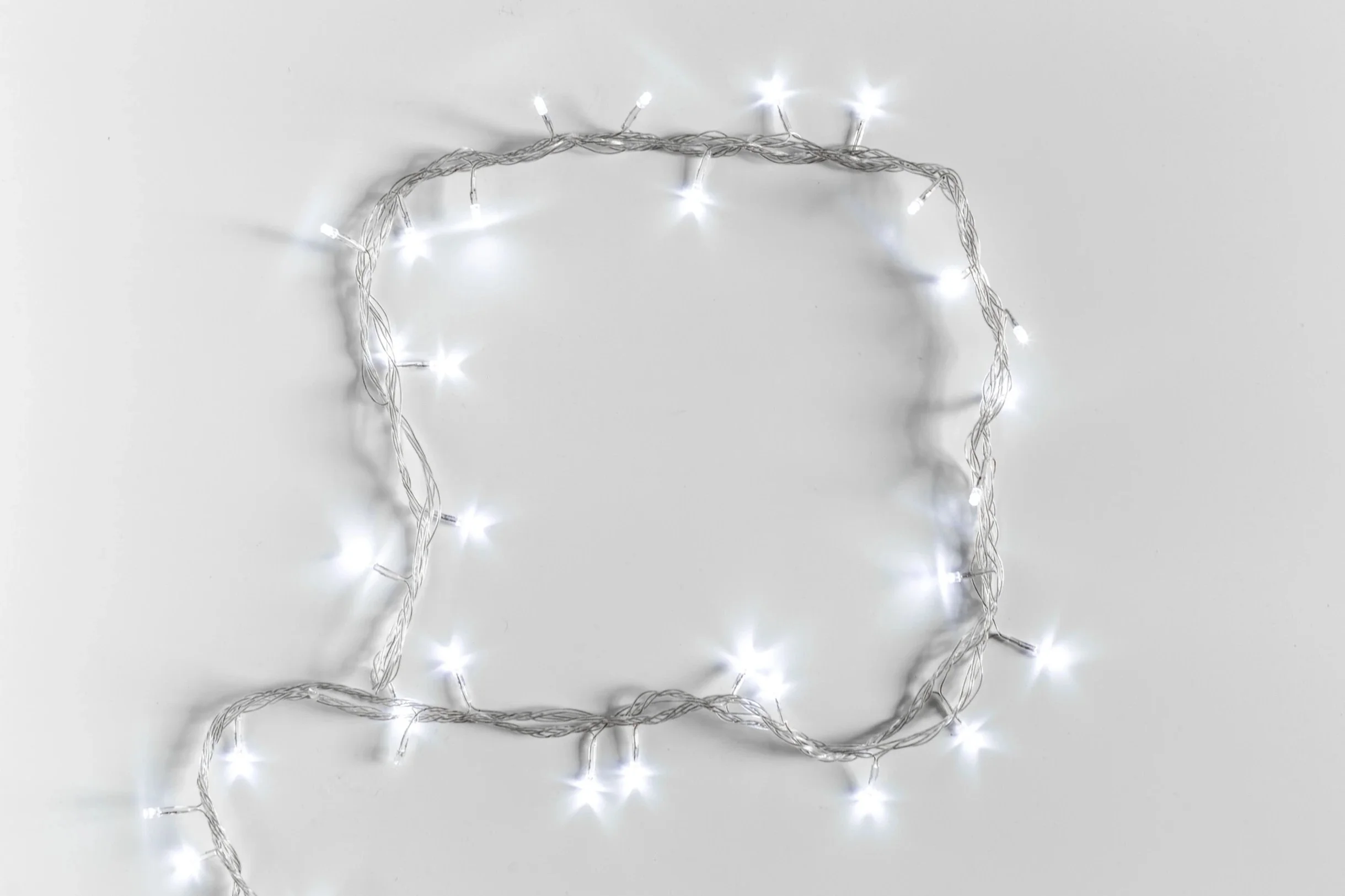 String of white Christmas lights loosely arranged on a light surface.