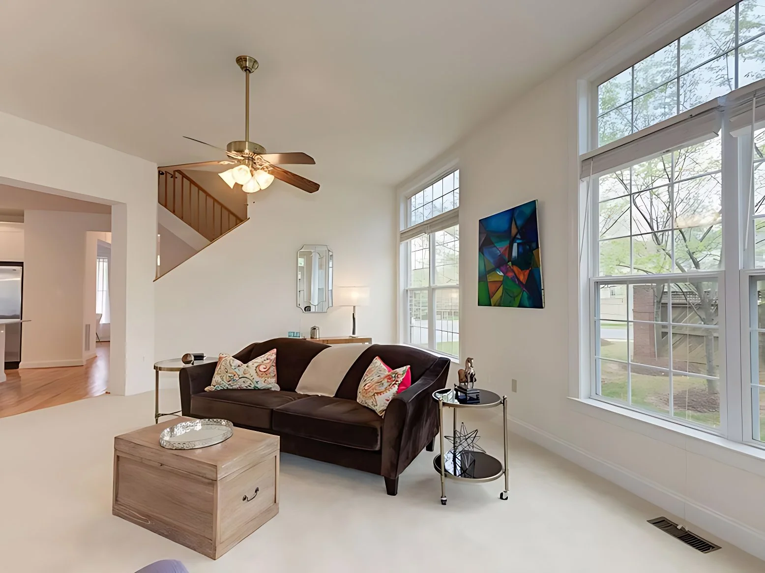 Bright living room with sofa, coffee table, large windows, and view into adjacent spaces.