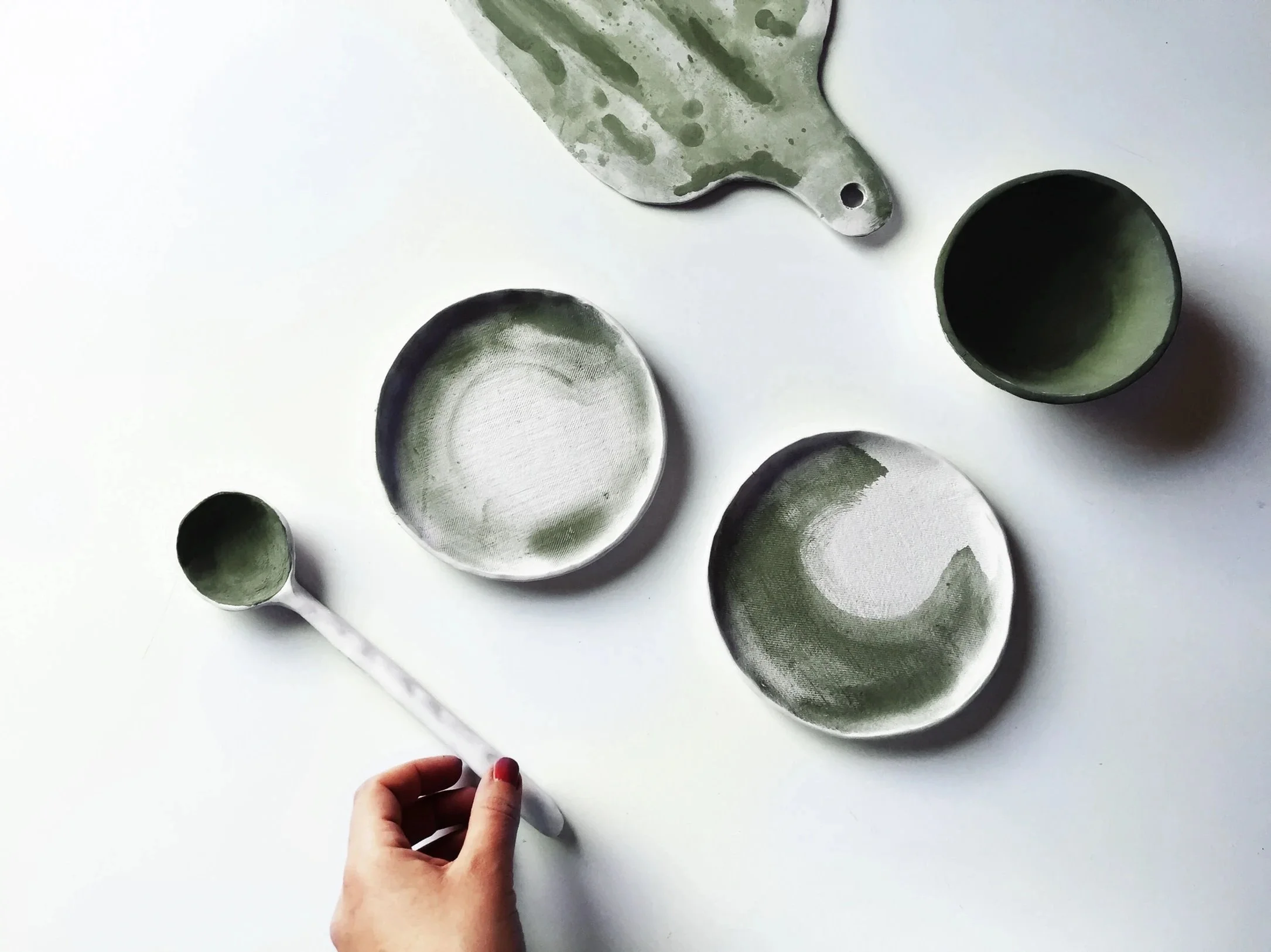 Minimal kitchen dishes and utensils arranged on a white surface.
