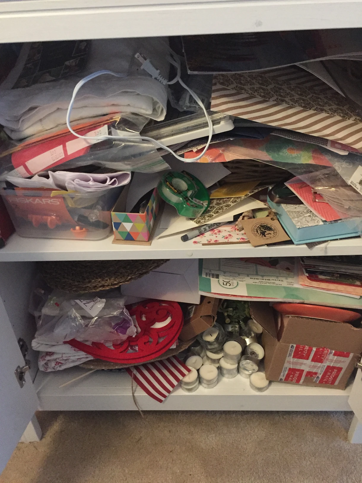 Cluttered cabinet filled with papers, containers, and miscellaneous household items.