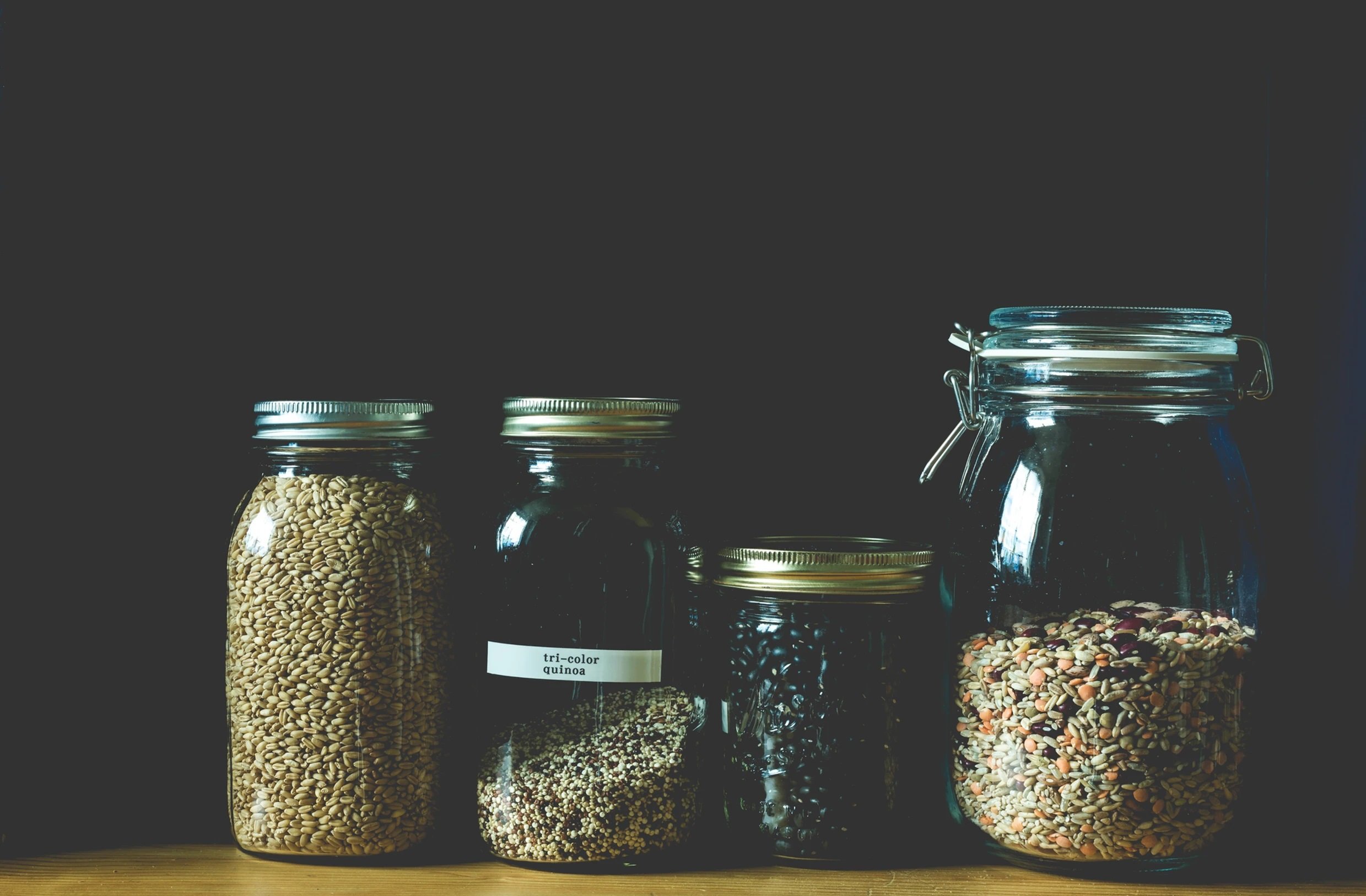 Glass jars with grains and spices neatly arranged on a shelf.