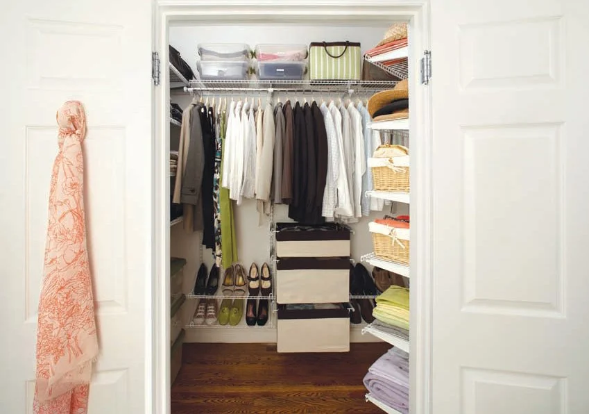 Organized closet with hanging clothes, folded items, shelves, and storage bins neatly arranged.