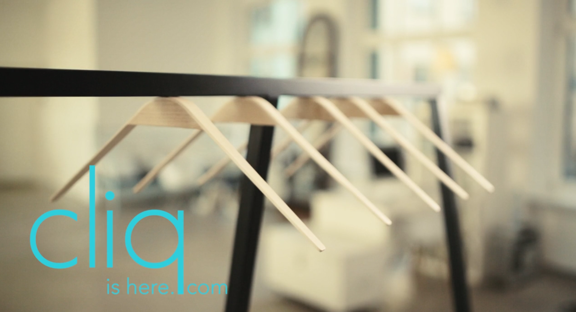 Minimal clothing rack with empty hangers and overlay text "cliq is here".