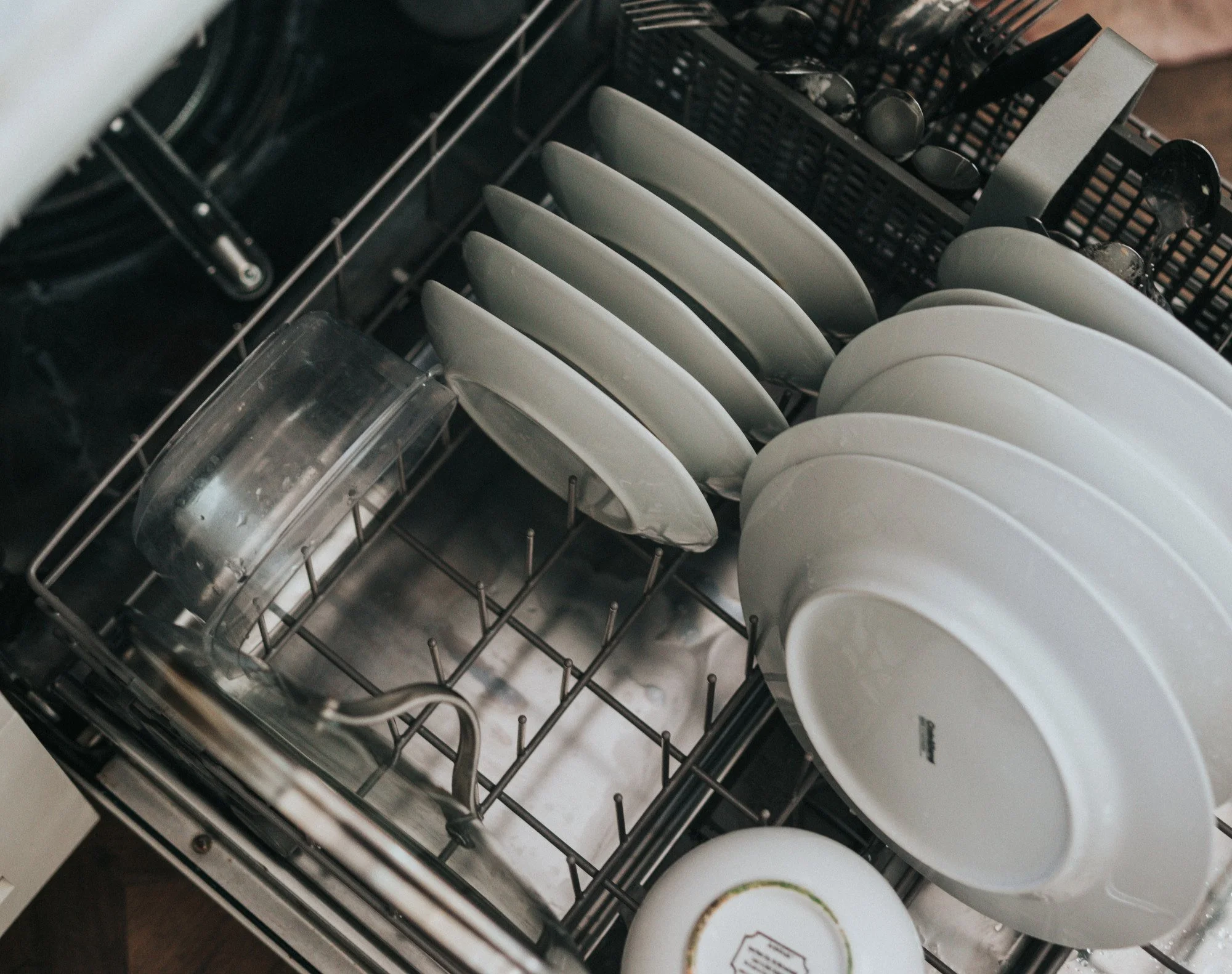 Open dishwasher with clean plates arranged on the rack.