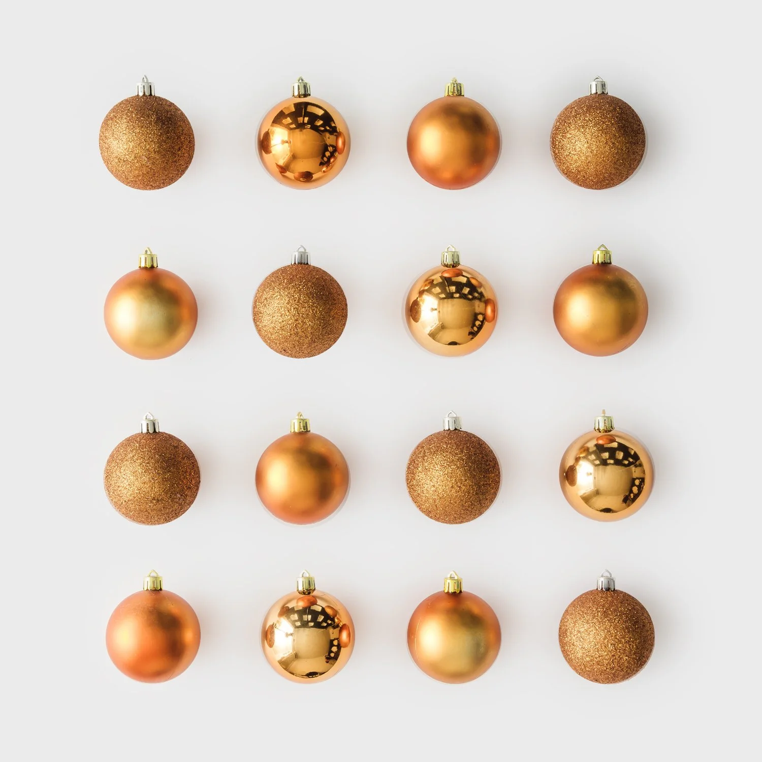 Set of gold Christmas ornaments arranged in a grid on a neutral background.