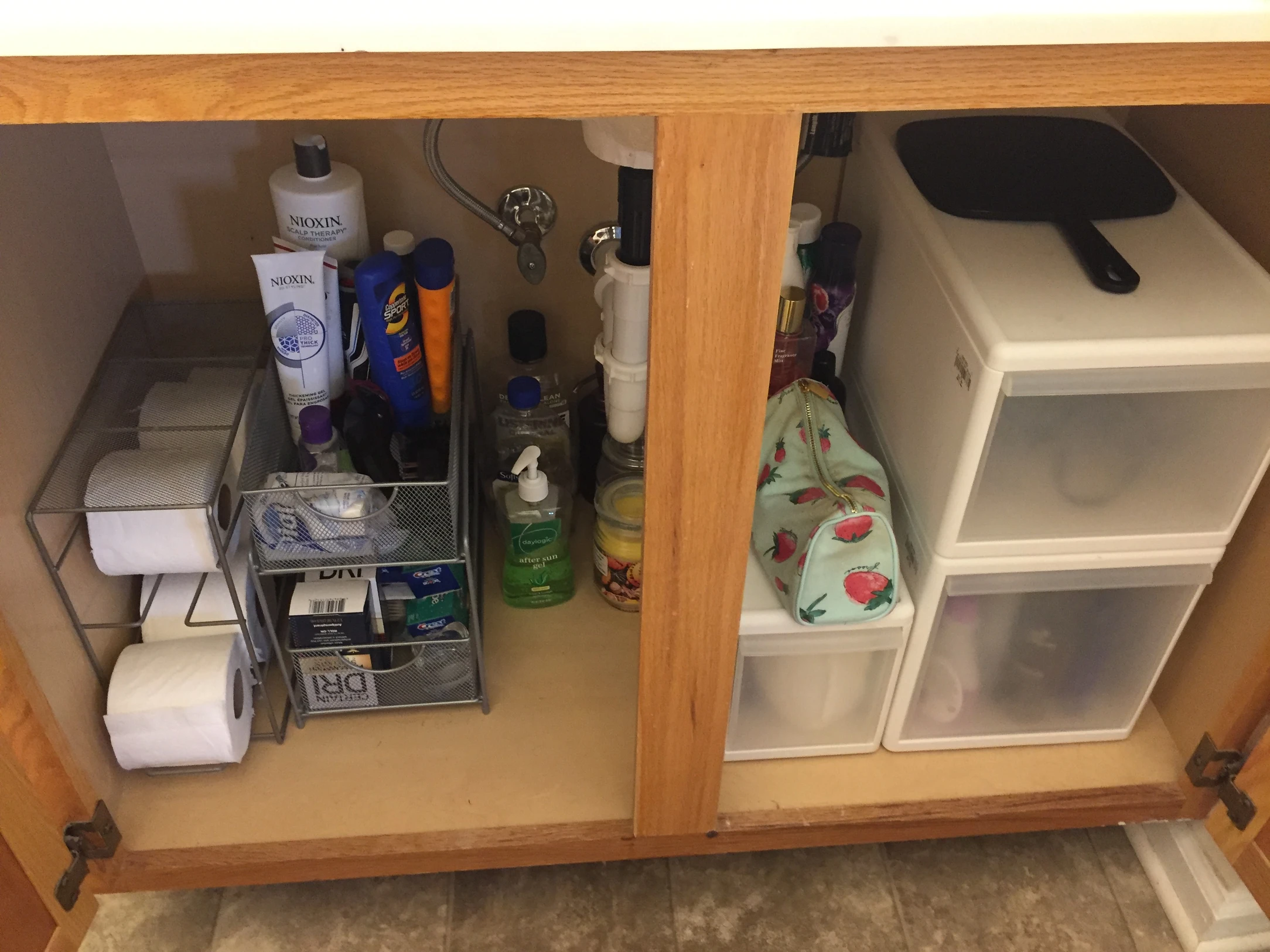 Bathroom cabinet neatly organized with storage bins and arranged toiletries after decluttering.