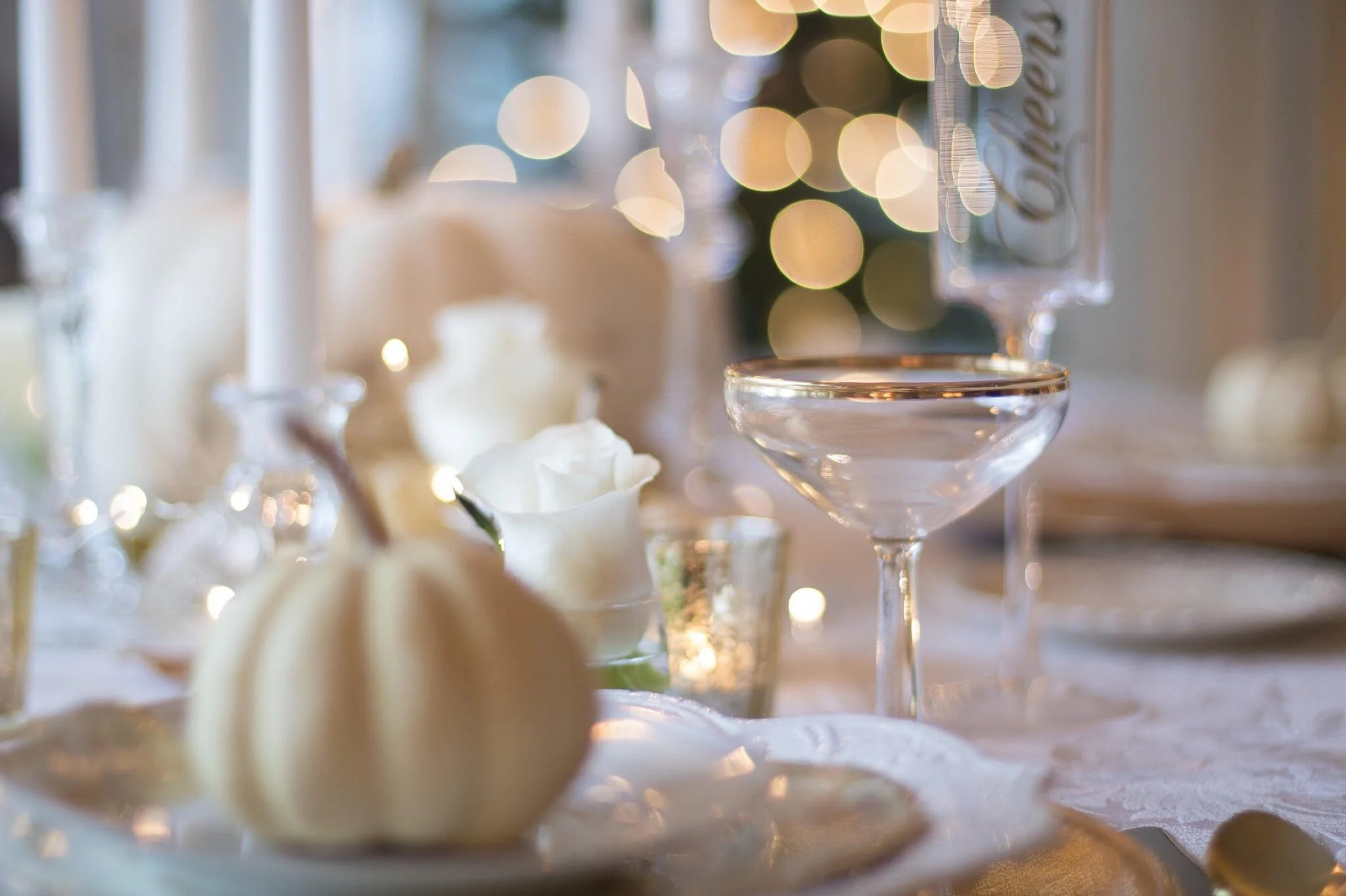 Festive holiday table setting with candles, glassware, and seasonal centerpiece.