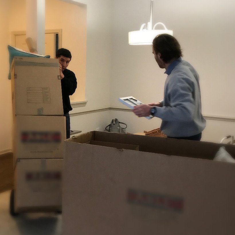 Movers handling large boxes during a home relocation process.