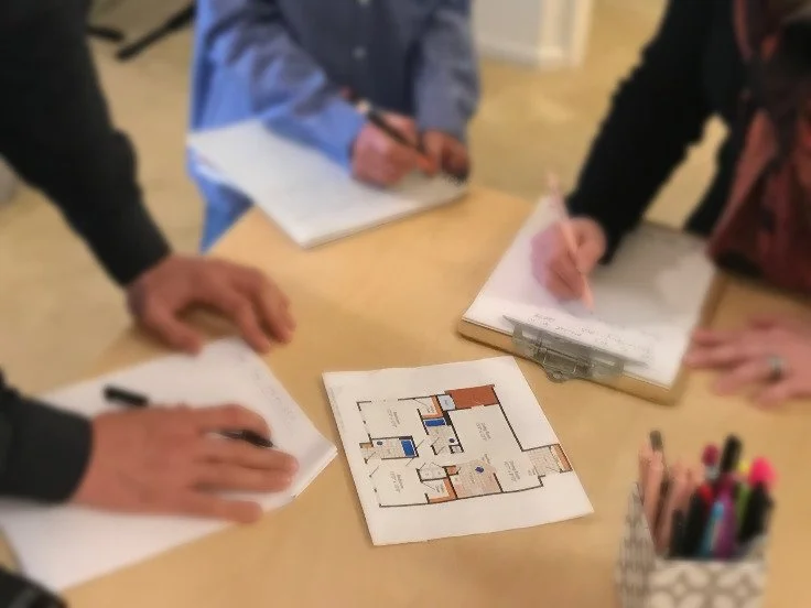 Close-up of hands planning layout with tablet and documents on a table.