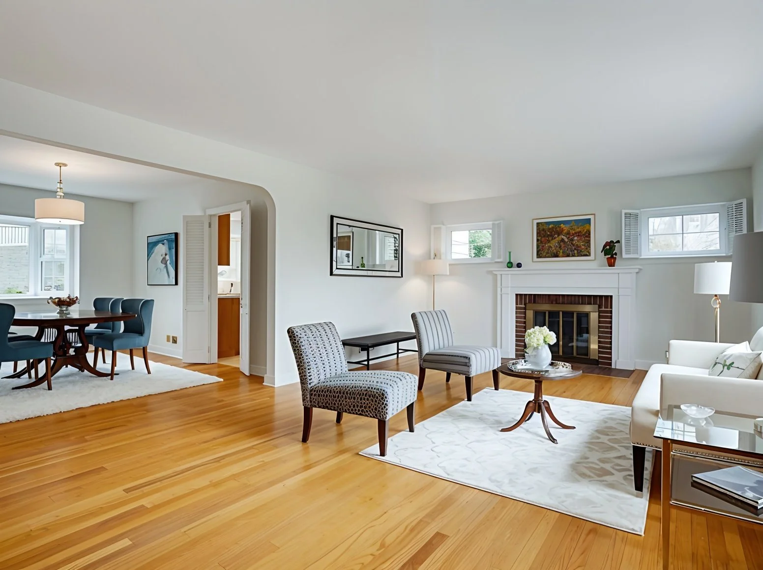Spacious living room with hardwood floors, two armchairs, fireplace, and open doorway to dining area.