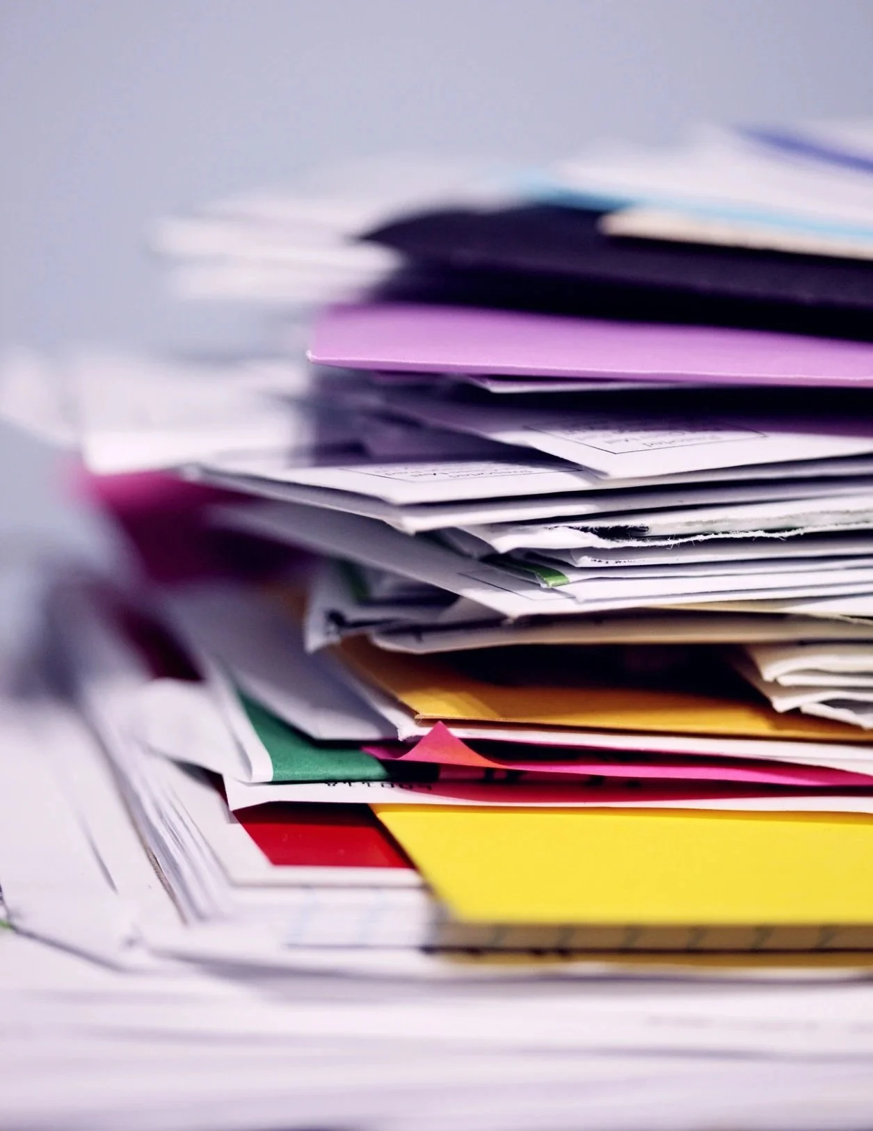 Stack of mixed paperwork and documents piled on a desk.