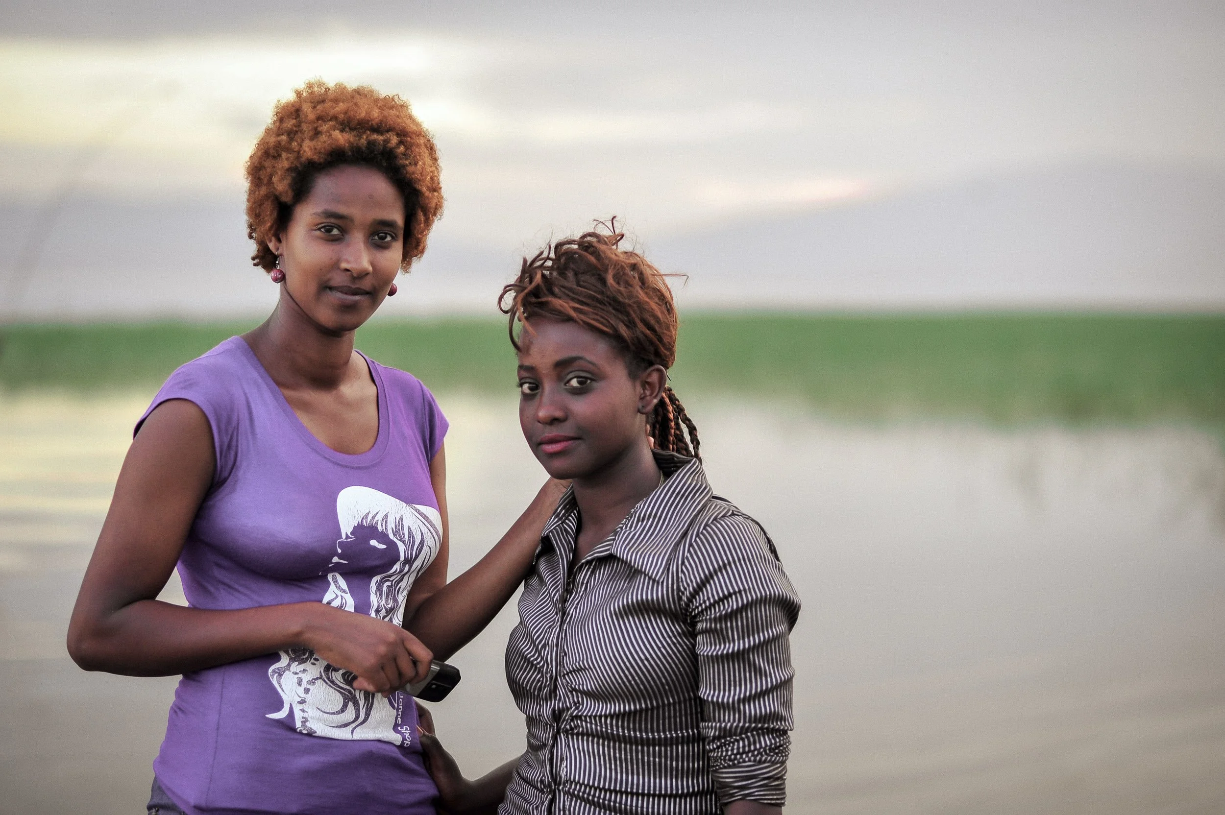 Deux femmes posant près d'un lac ou d'une rivière avec un horizon dégagé dans un paysage naturel