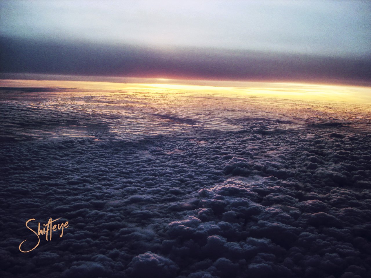 Clouds during sunset from an aerial view, showing a dramatic sky with dark and light layers of clouds.