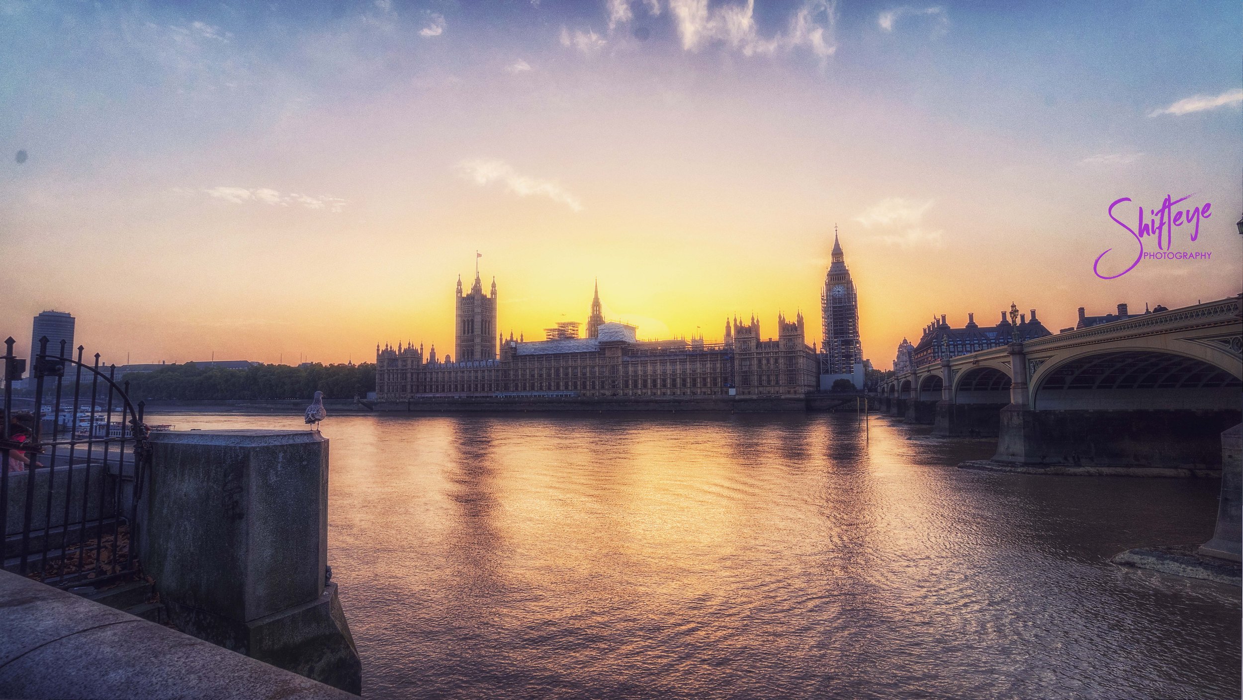 Sunset view of the Houses of Parliament and Big Ben across the River Thames in London, with Westminster Bridge on the right.