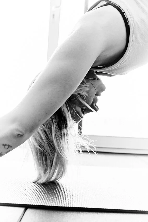 A woman practicing yoga in a headstand position indoors on a yoga mat.