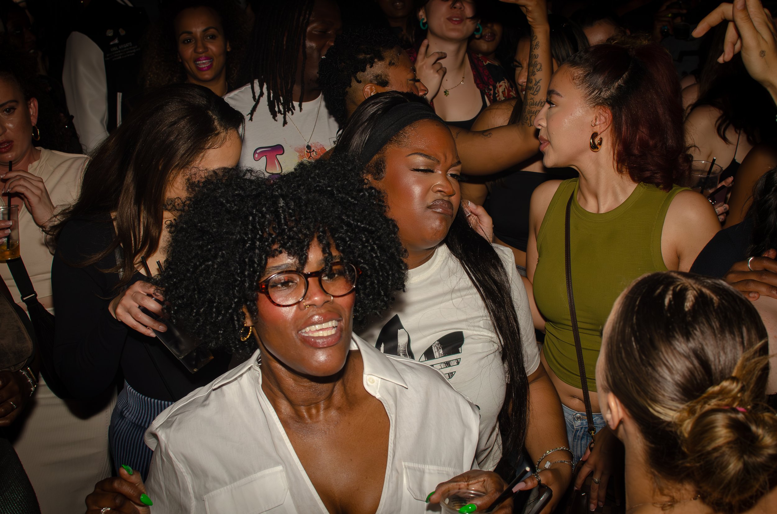 A group of people enjoying a party or nightclub, with individuals dancing, socializing, and holding drinks.